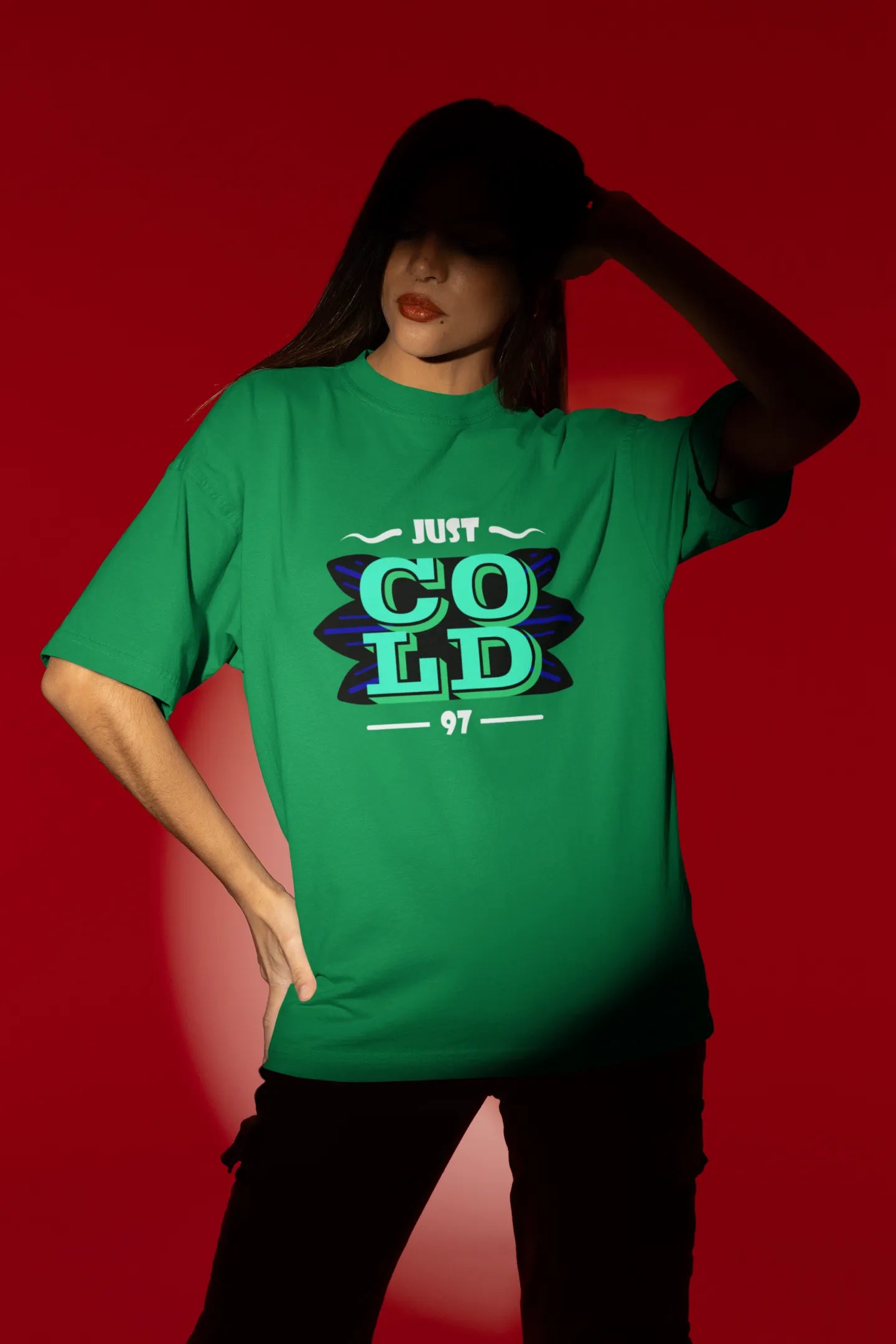 Third front view of a female model wearing an forest green oversized t-shirt with the text "Just Cold" printed on it.
