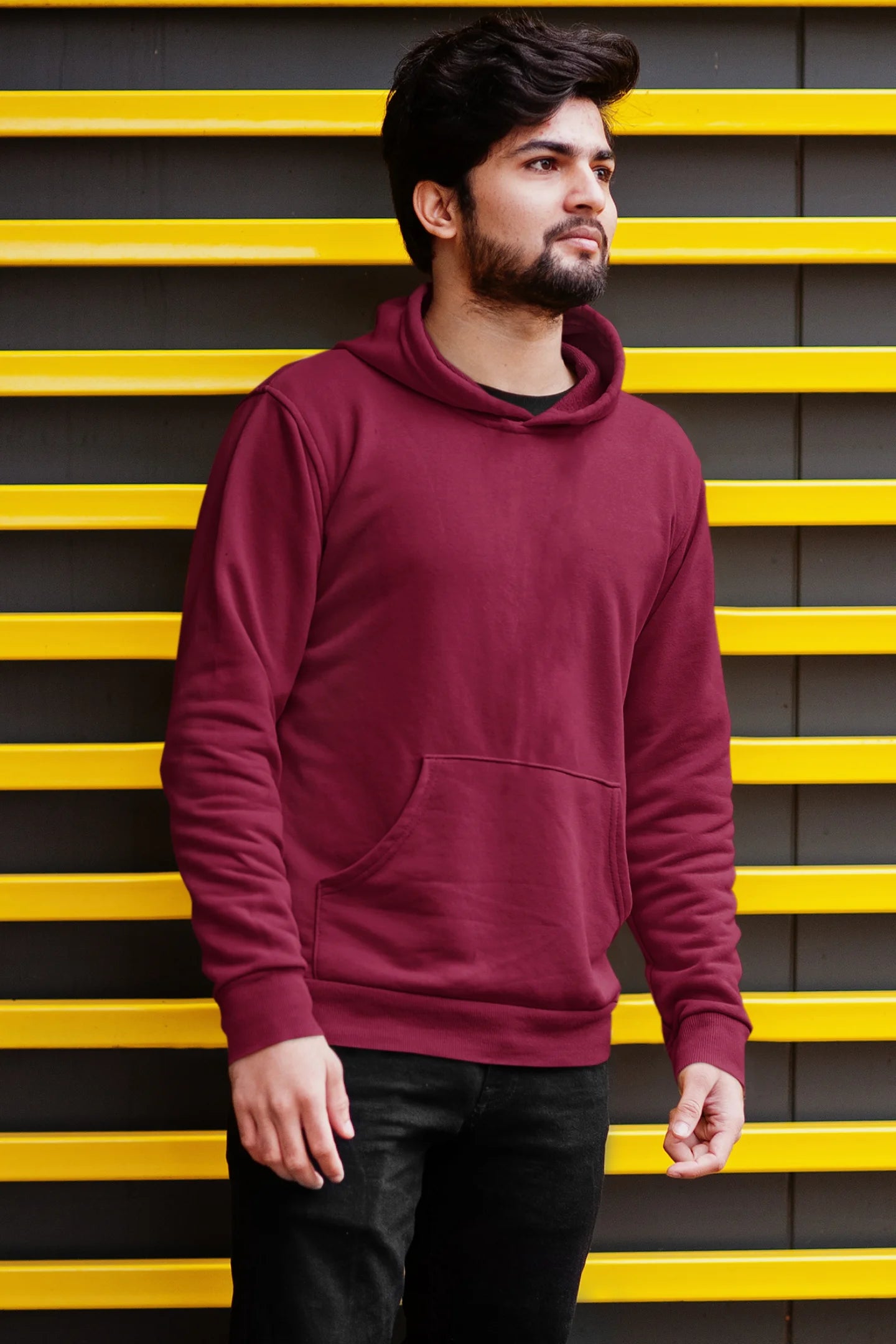 Second front view of a male model wearing a maroon hoodie with a heron taking off under the moonlight.