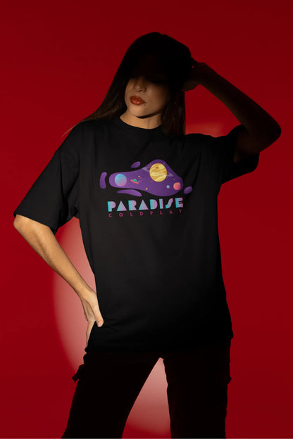 Fourth front view of a female model wearing an black oversized t-shirt with the "Paradise" album artwork by Coldplay.
