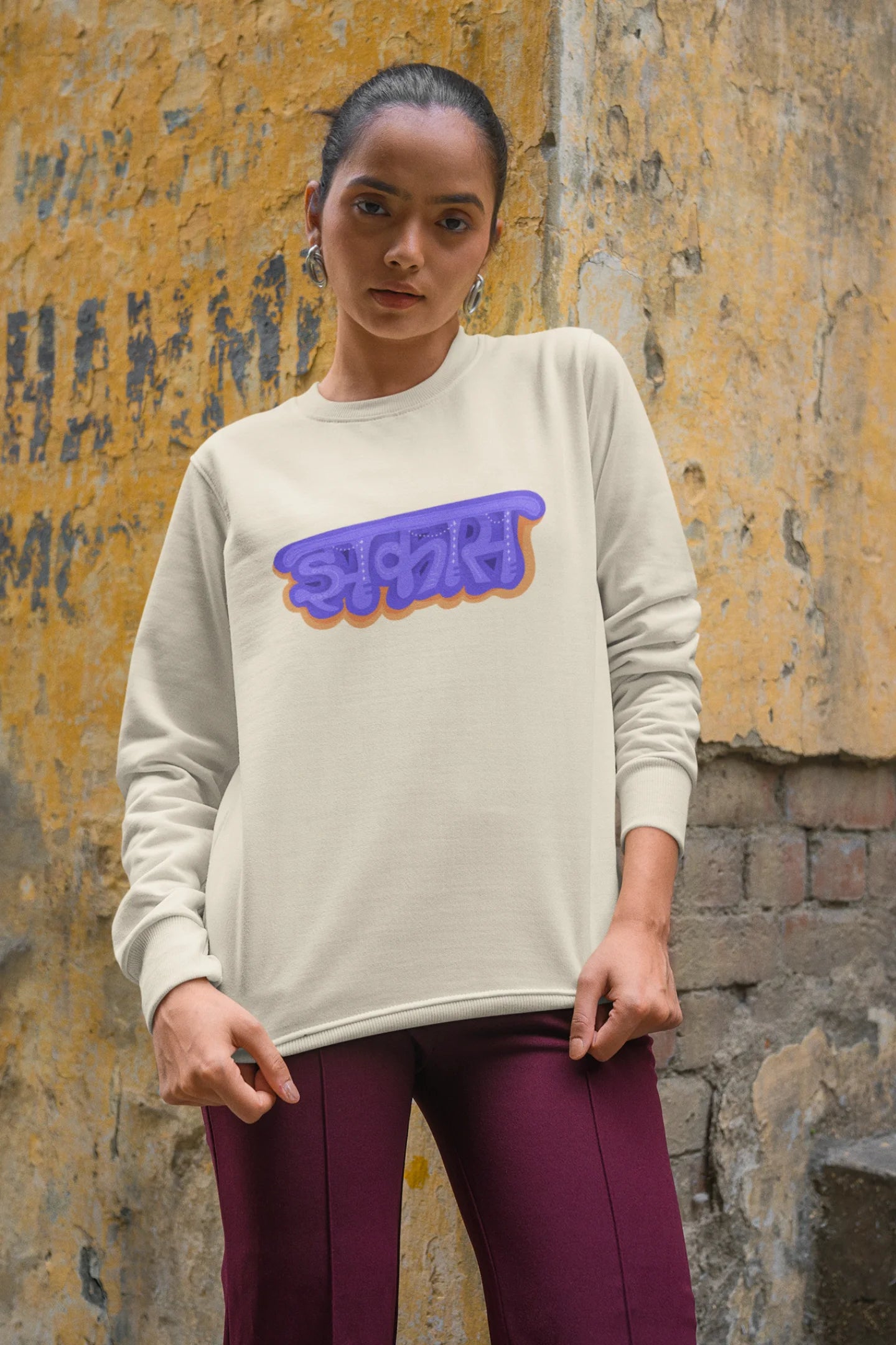 3rd front view of a female model wearing an cream sweatshirt featuring "Jhakas" in a stylish font.