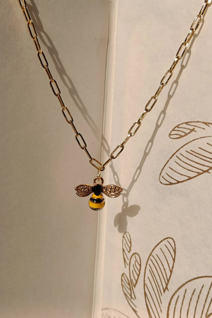 5th view of a gold chain necklace with a small pendant shaped like a honey bee.