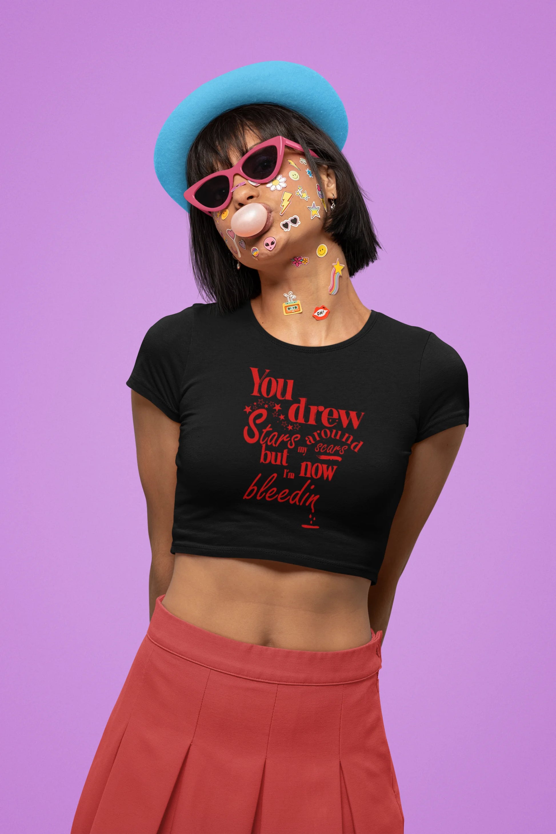 Second front view of a female model wearing a black crop top featuring the lyrics "You drew stars around my scars but now I'm bleeding," perfect for Swiftie fans.