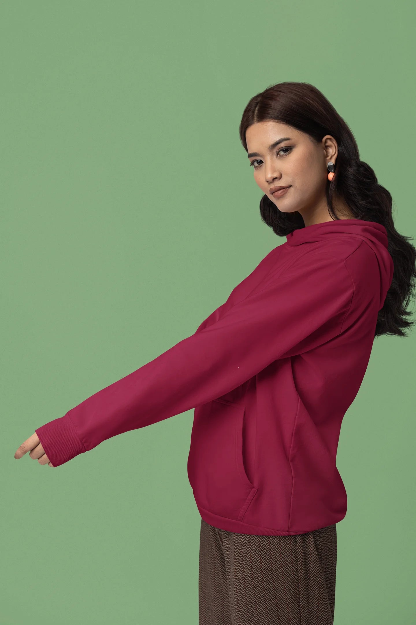 Third front view of a female model wearing a maroon hoodie with a heron taking off under the moonlight.