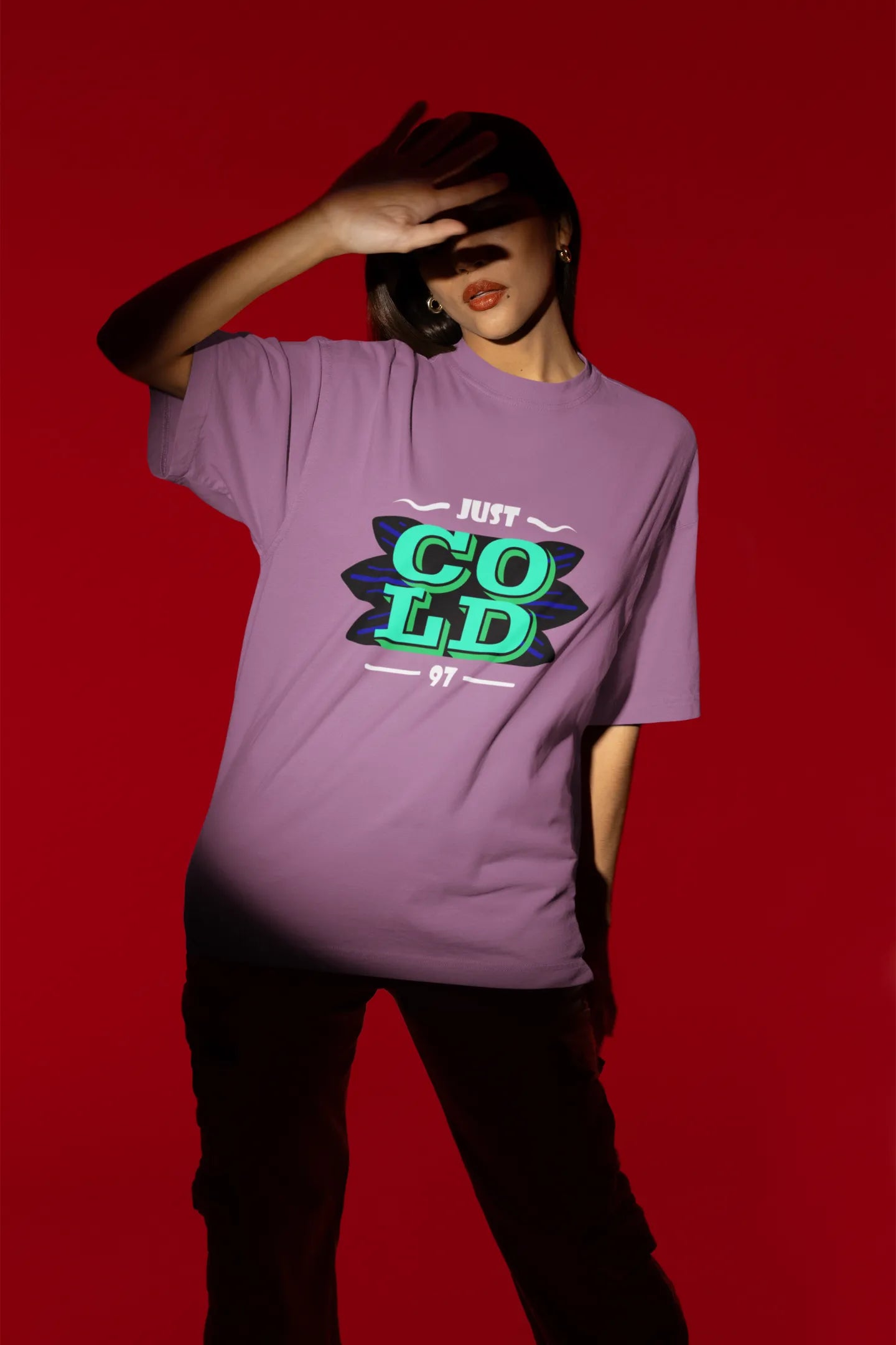 Fourth front view of a female model wearing an dirty purple oversized t-shirt with the text "Just Cold" printed on it.