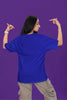 Back view of a female model wearing a royal blue oversized t-shirt with the text 