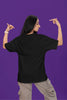 Back view of a female model wearing a black oversized t-shirt with the text 