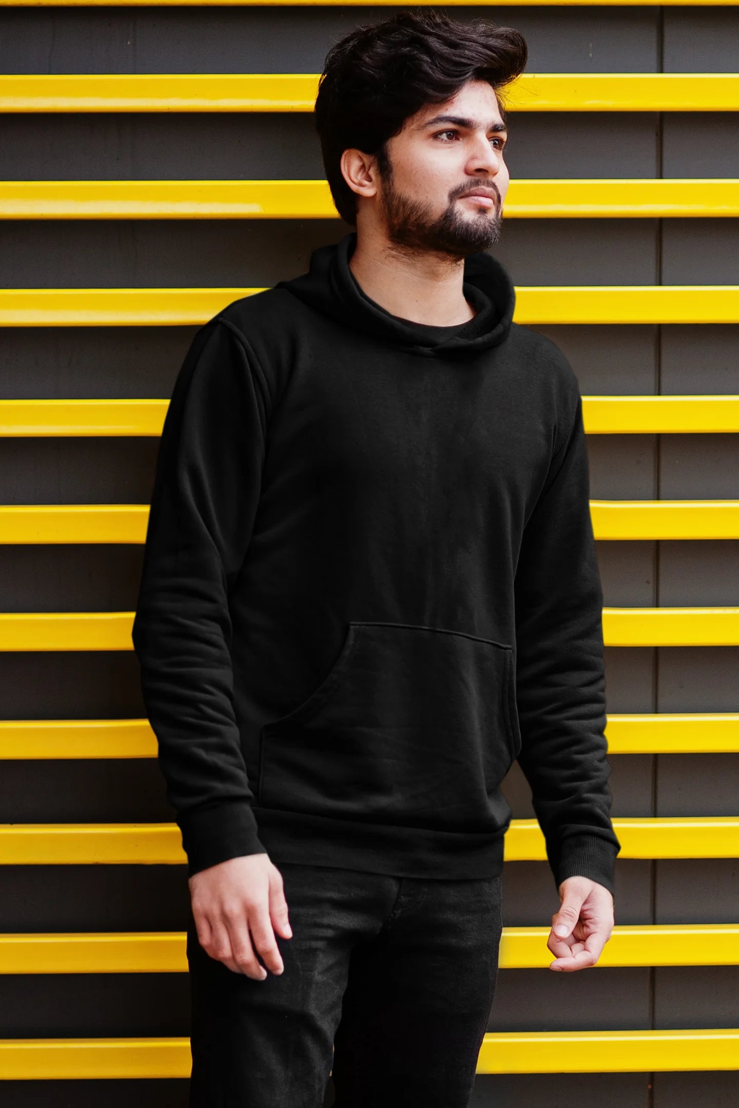 First front view of a male model wearing a black hoodie with a heron taking off under the moonlight.