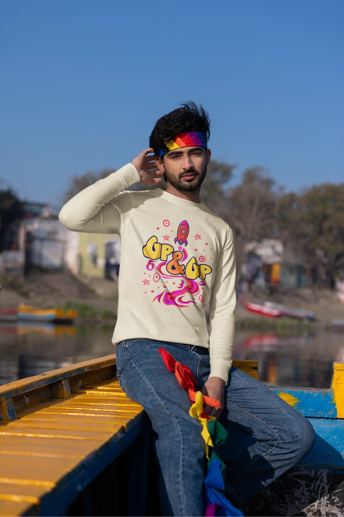 First front view of a male model wearing an cream sweatshirt with a rocket ship design and the text "Up & Up".