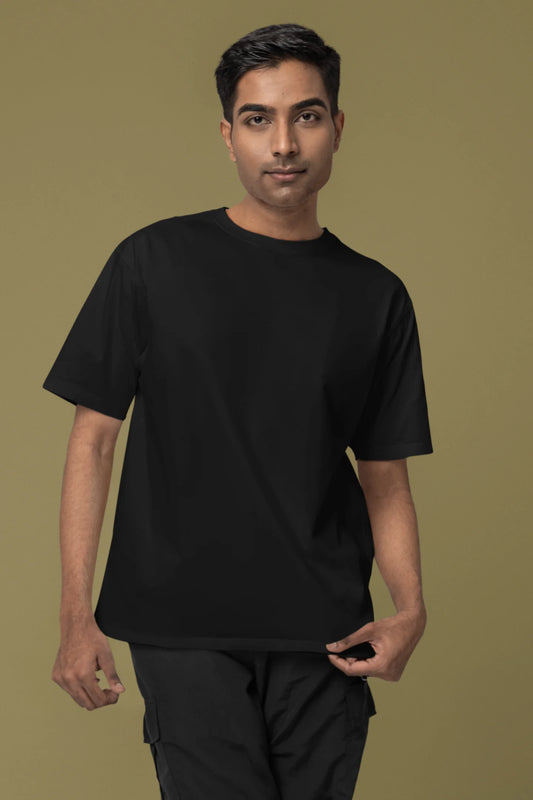 Front view of a male model wearing a black oversized tee with a heron taking off under the moonlight.