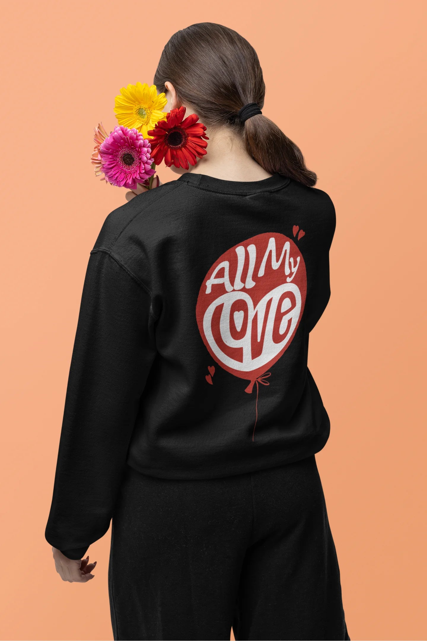 Back view of a female model wearing a Black sweatshirt with a heart design and the text "All My Love".