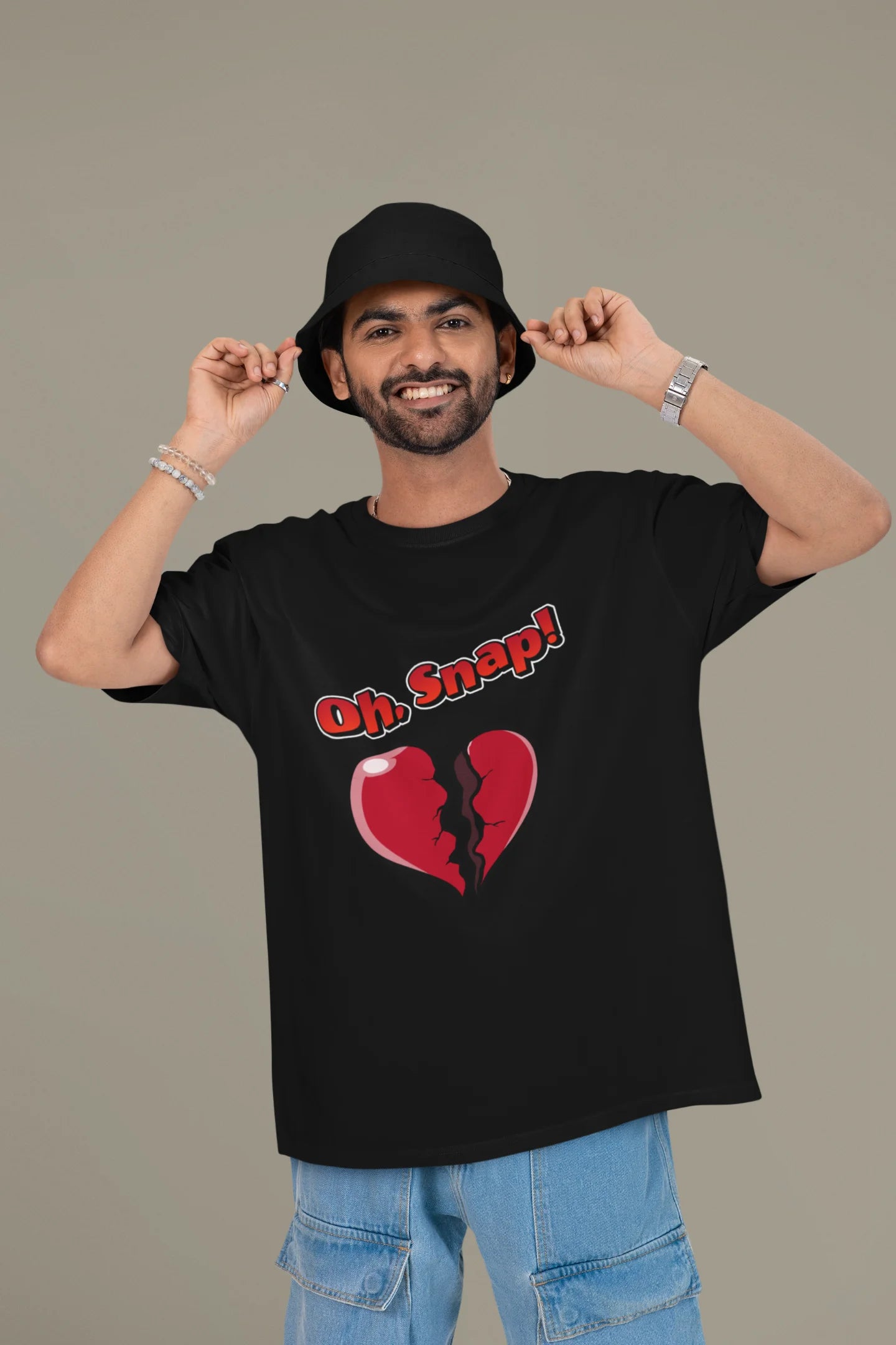 First front view of a male model wearing a black oversized t-shirt with the text "Oh Snap!" and a broken heart symbol underneath.