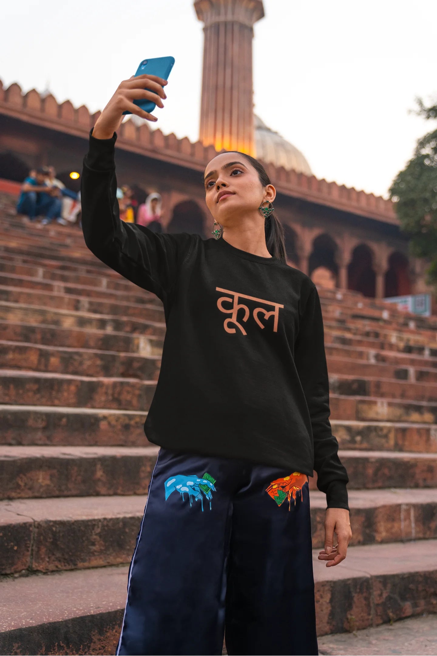 3rd front view of a female model wearing a black oversized t-shirt featuring the Hindi word for "cool" with a unique, playful design.