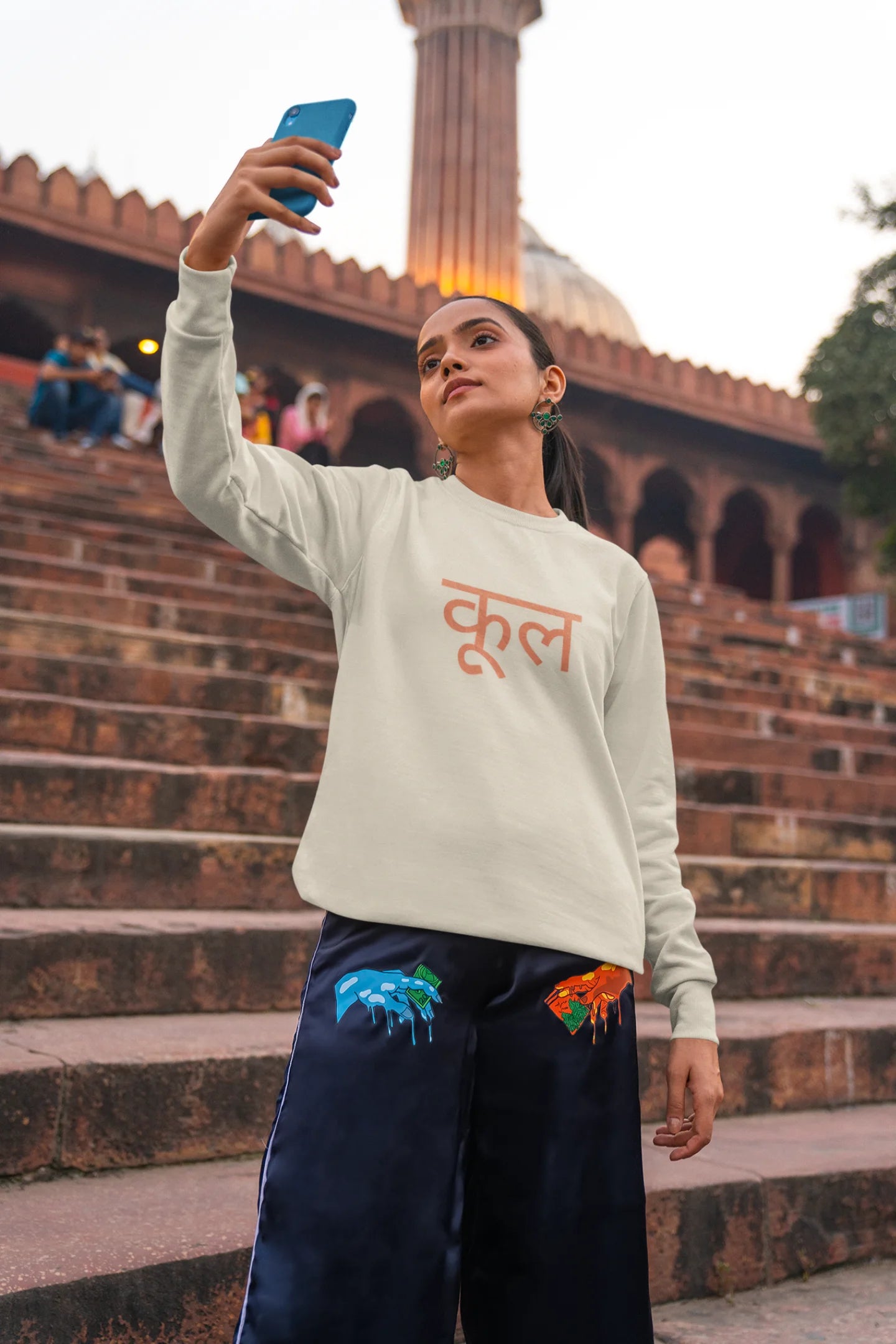 6th front view of a female model wearing a cream oversized t-shirt featuring the Hindi word for "cool" with a unique, playful design.