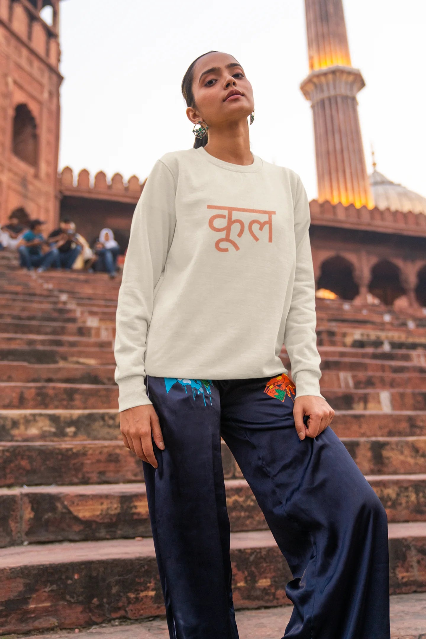 First front view of a female model wearing a cream oversized t-shirt featuring the Hindi word for "cool" with a unique, playful design.