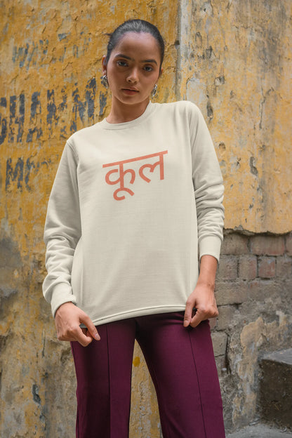 2nd front view of a female model wearing a cream oversized t-shirt featuring the Hindi word for "cool" with a unique, playful design.