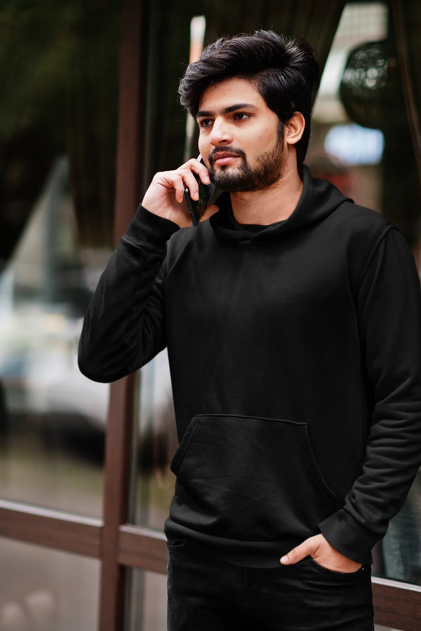 Fourth front view of a male model wearing a black hoodie featuring a Range Rover Defender design, exuding power and ruggedness.