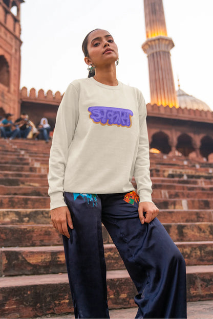 6th front view of a female model wearing an cream sweatshirt featuring "Jhakas" in a stylish font.