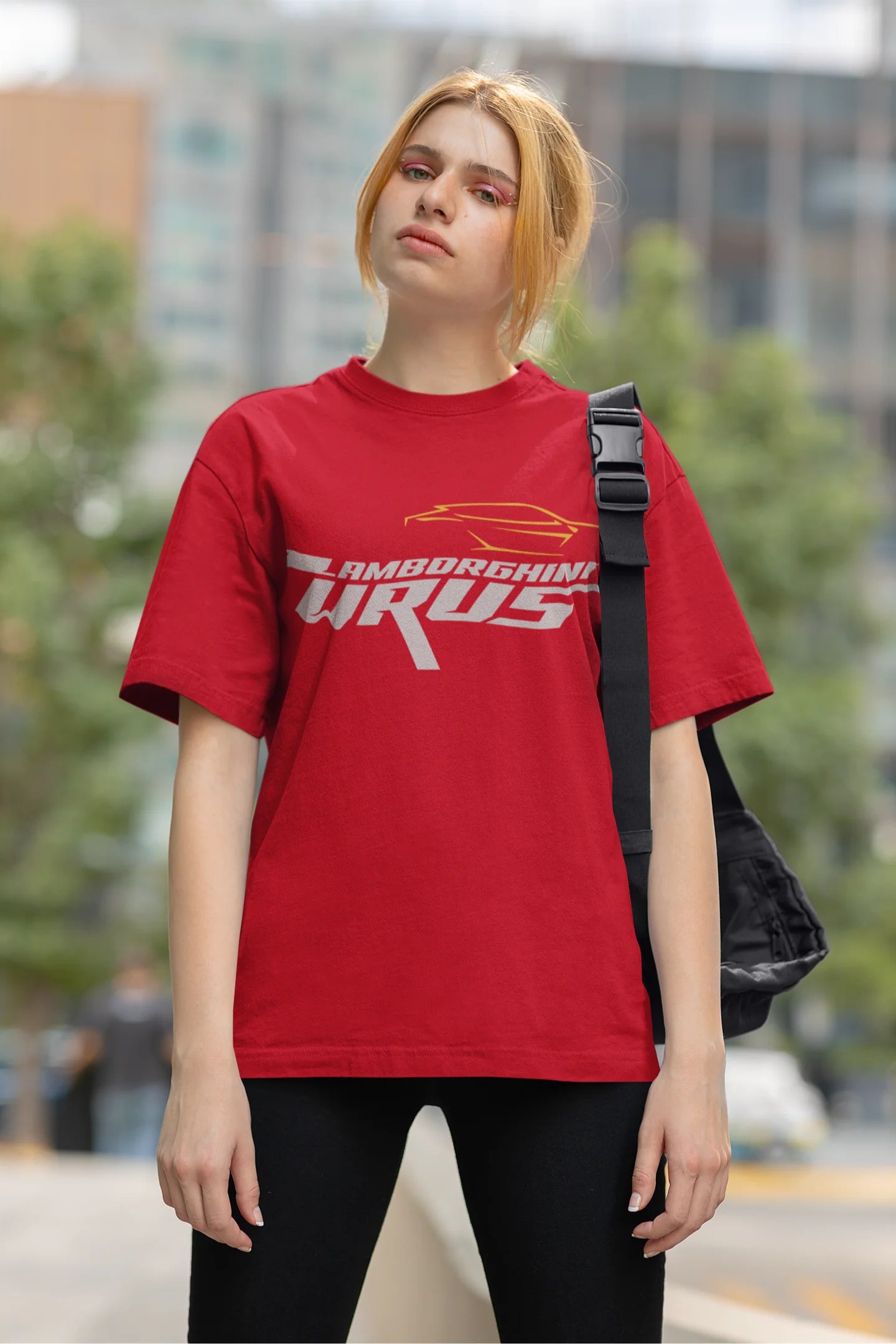 Front view of a female model wearing a red oversized t-shirt featuring a design of a Lamborghini Urus.