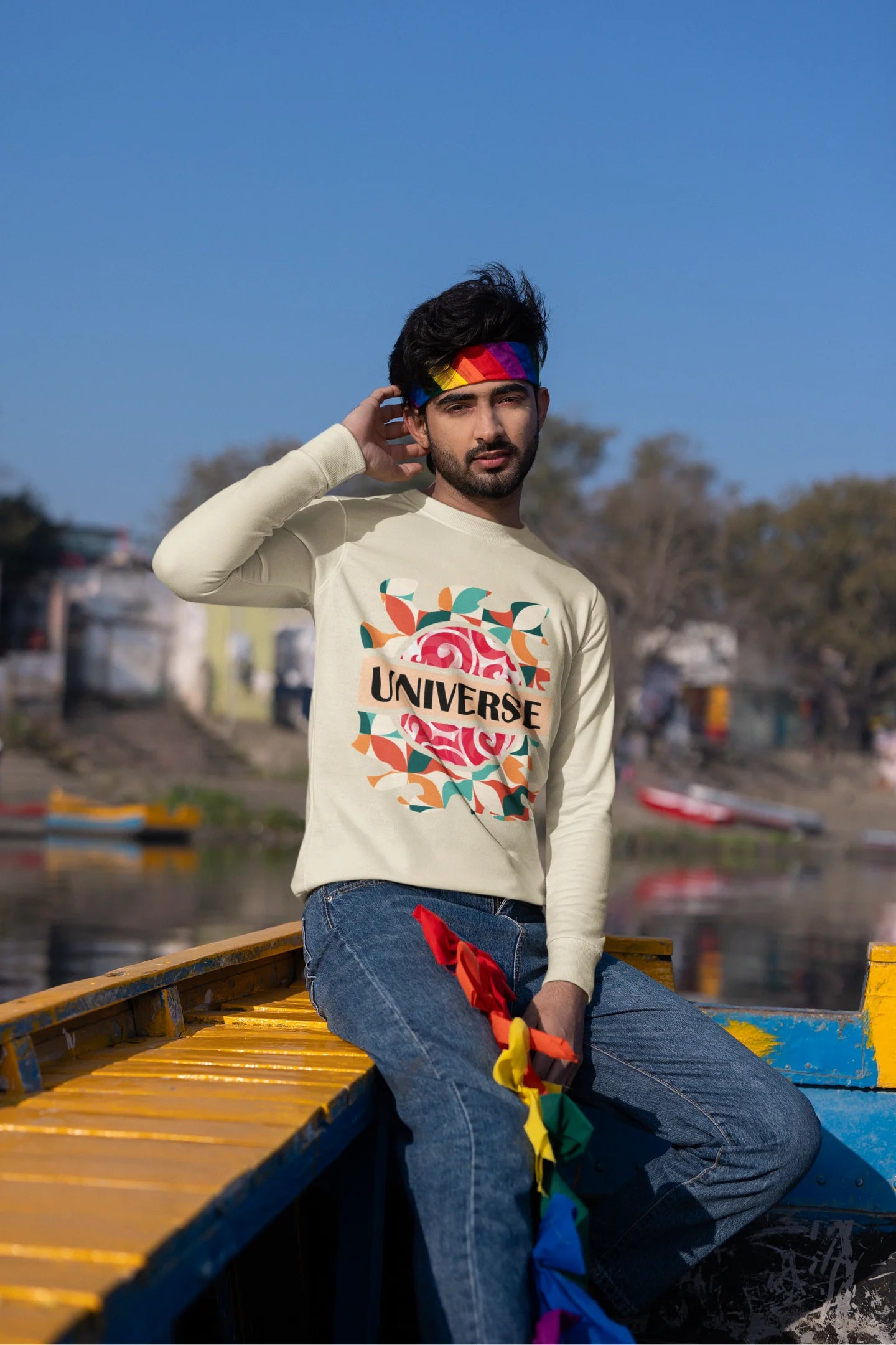 Third front view of a male model wearing an cream sweatshirt with a cosmic Universe design inspired by Coldplay.