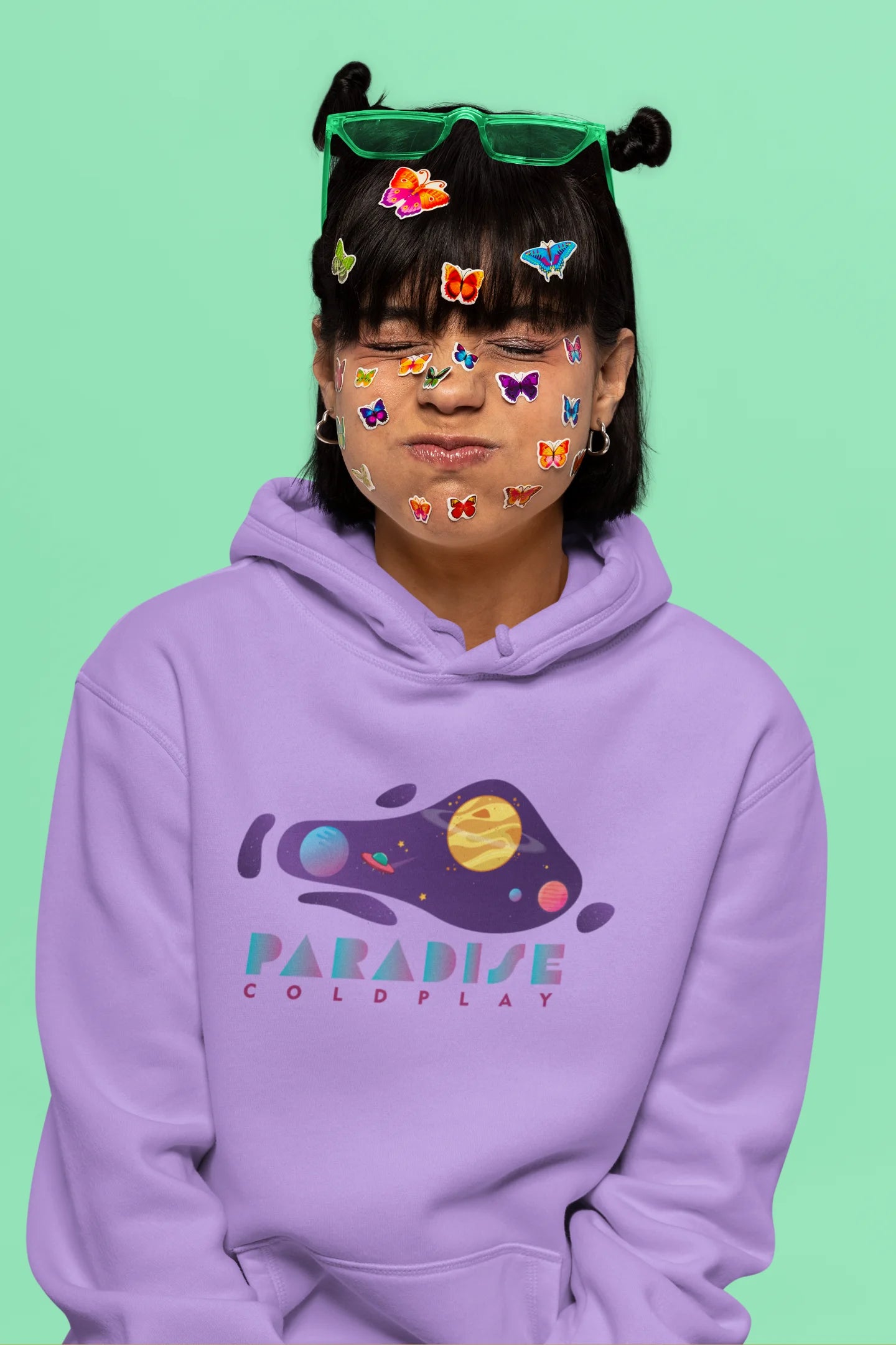 6th front view of a female model wearing an lavender hoodie with the "Paradise" album artwork by Coldplay.