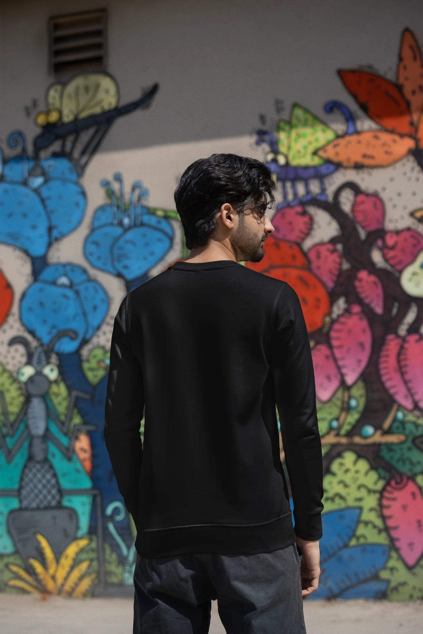 Back view of a male model wearing an black sweatshirt with a cosmic Universe design inspired by Coldplay.