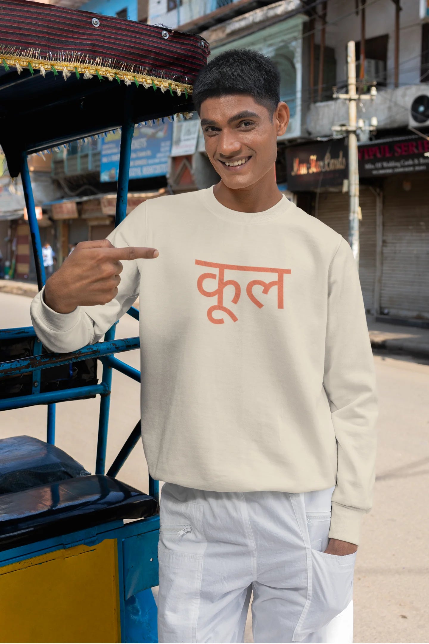 4th front view of a male model wearing a cream oversized t-shirt featuring the Hindi word for "cool" with a unique, playful design.