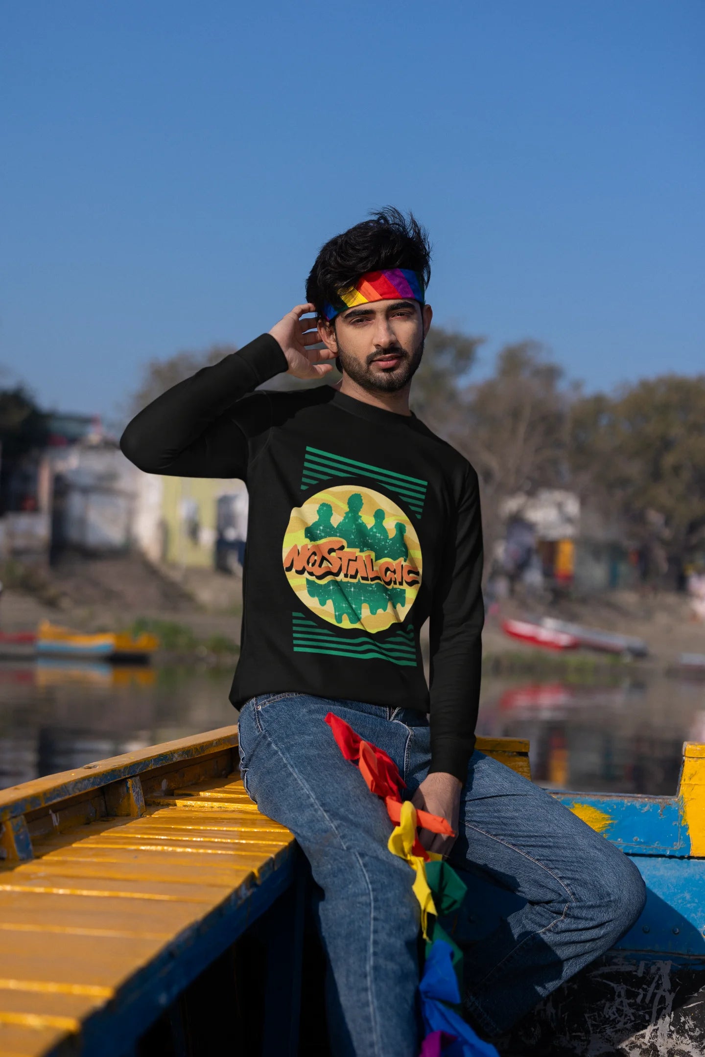 First view of a male model wearing an oversized black sweatshirt with a shadow silhouette of the Coldplay band members and the word "Nostalgic" printed on it.