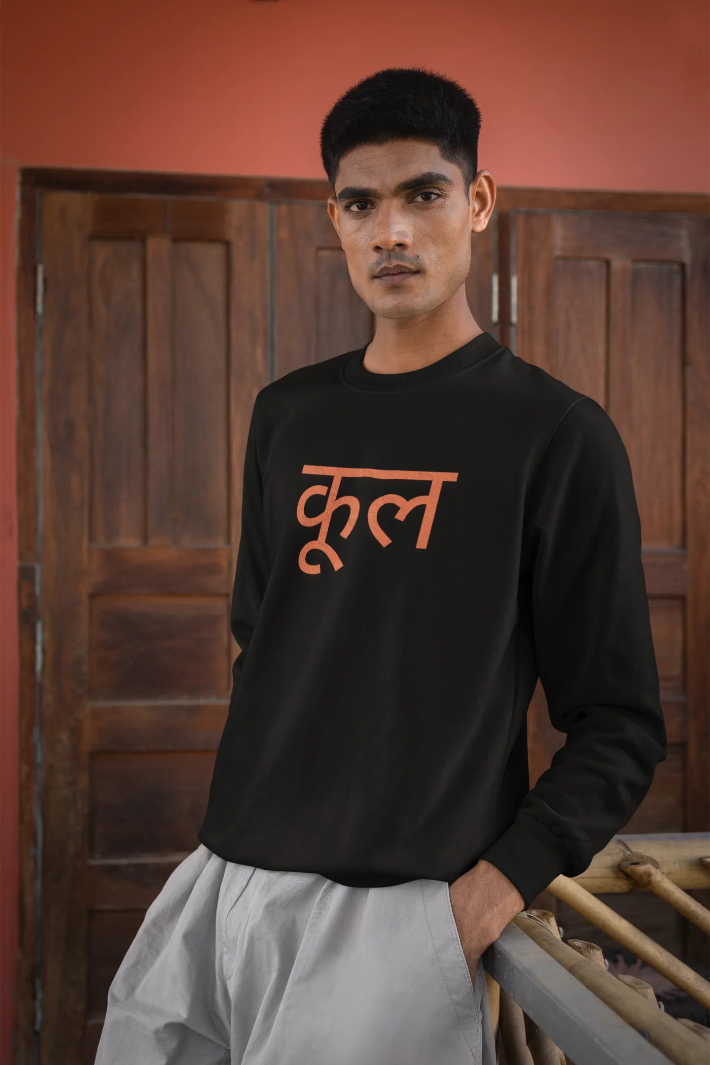 4th front view of a male model wearing a black oversized t-shirt featuring the Hindi word for "cool" with a unique, playful design.