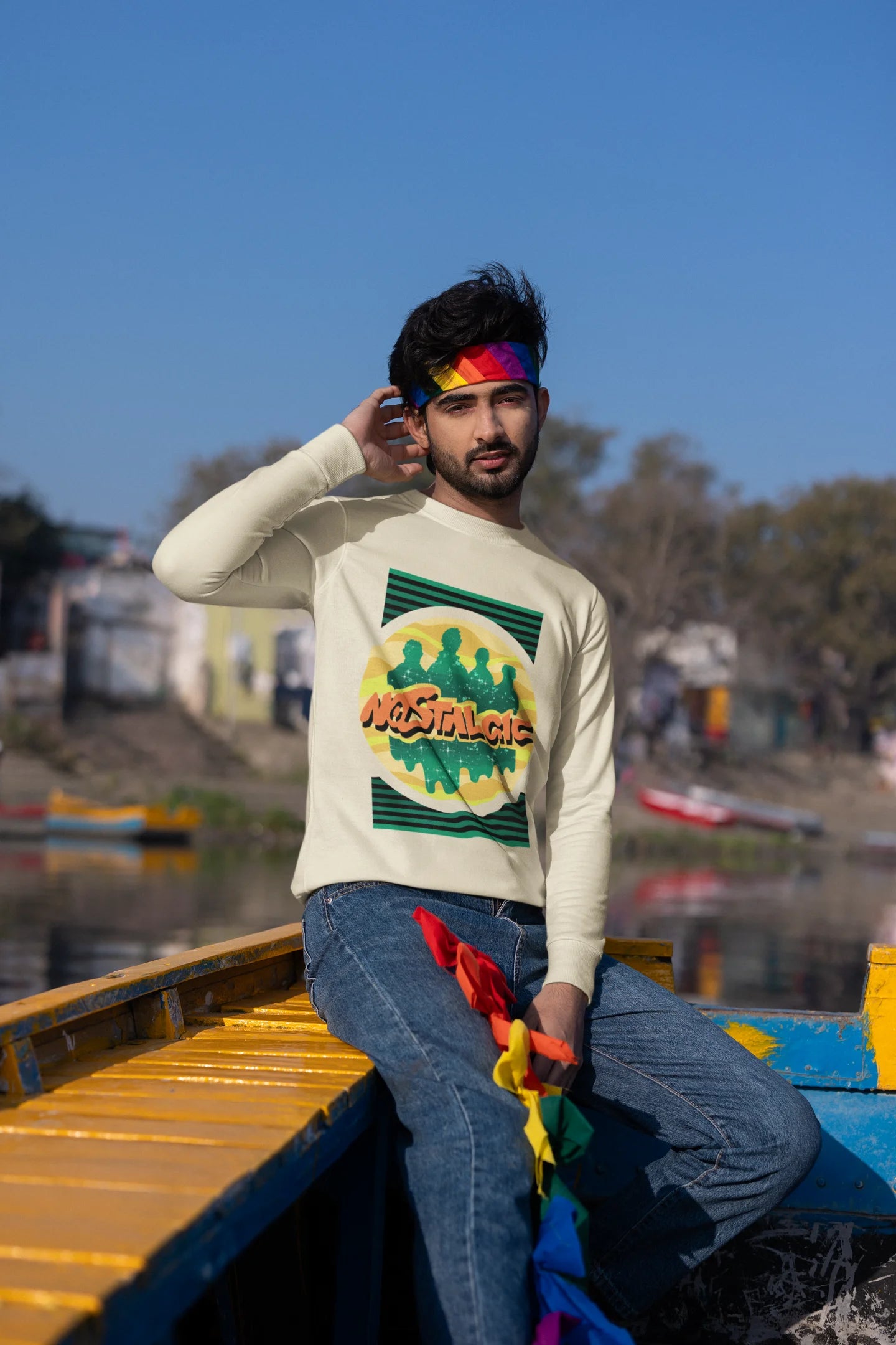 First view of a male model wearing an oversized cream sweatshirt with a shadow silhouette of the Coldplay band members and the word "Nostalgic" printed on it.