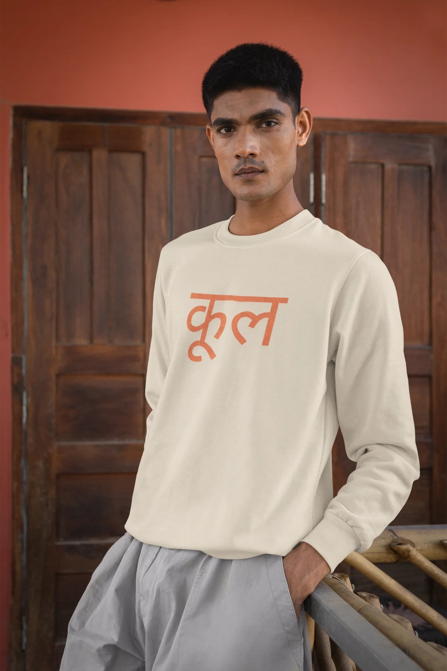 5th front view of a male model wearing a cream oversized t-shirt featuring the Hindi word for "cool" with a unique, playful design.