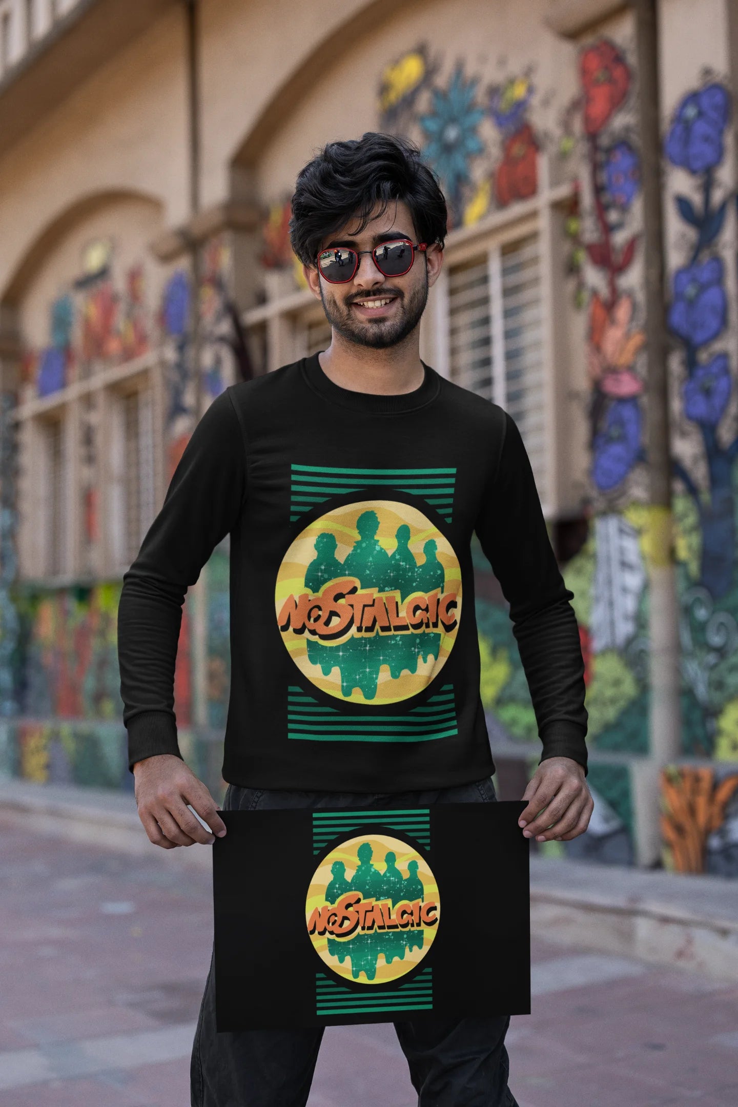 Second view of a male model wearing an oversized black sweatshirt with a shadow silhouette of the Coldplay band members and the word "Nostalgic" printed on it.