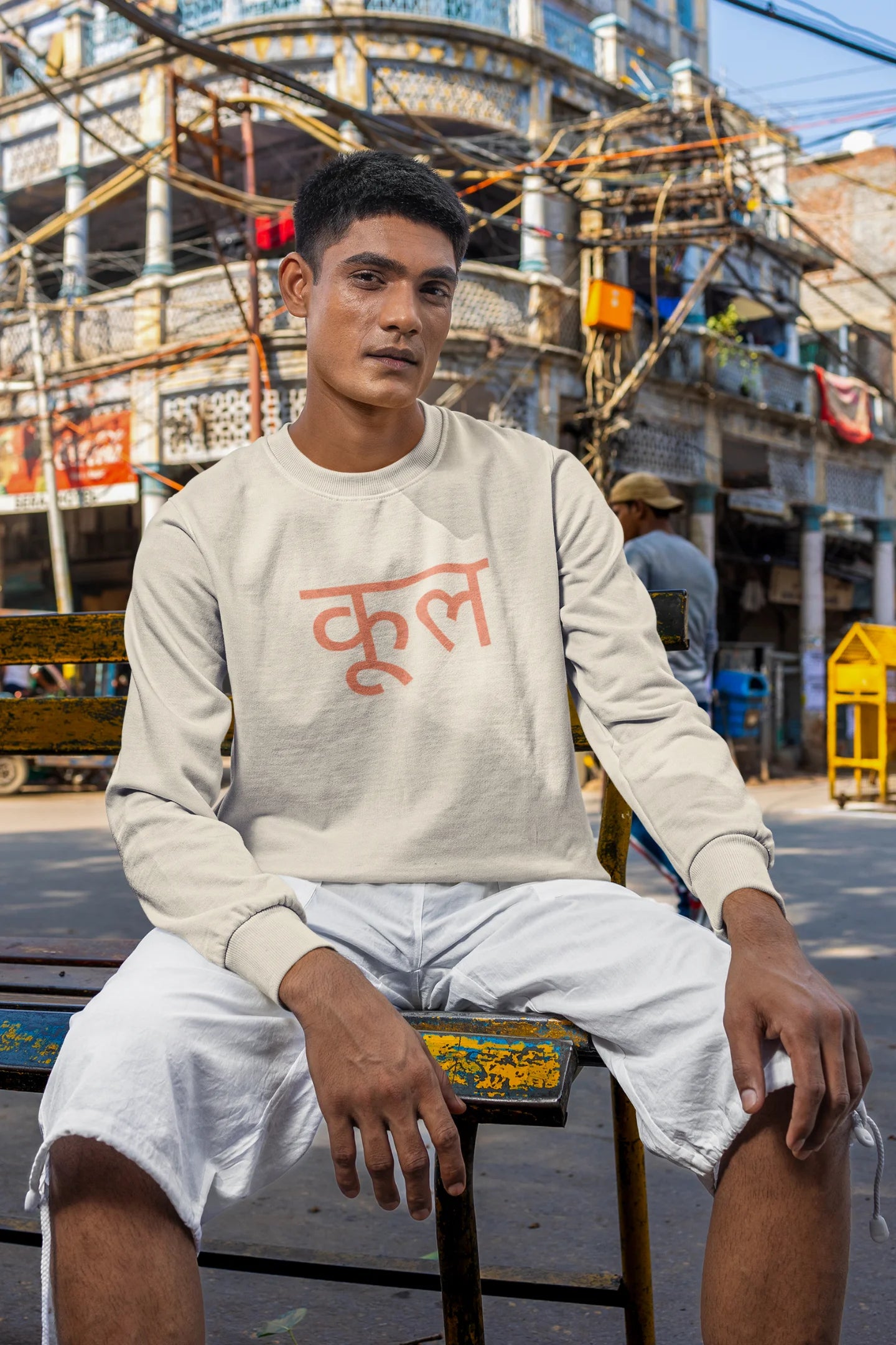 2nd front view of a male model wearing a cream oversized t-shirt featuring the Hindi word for "cool" with a unique, playful design.