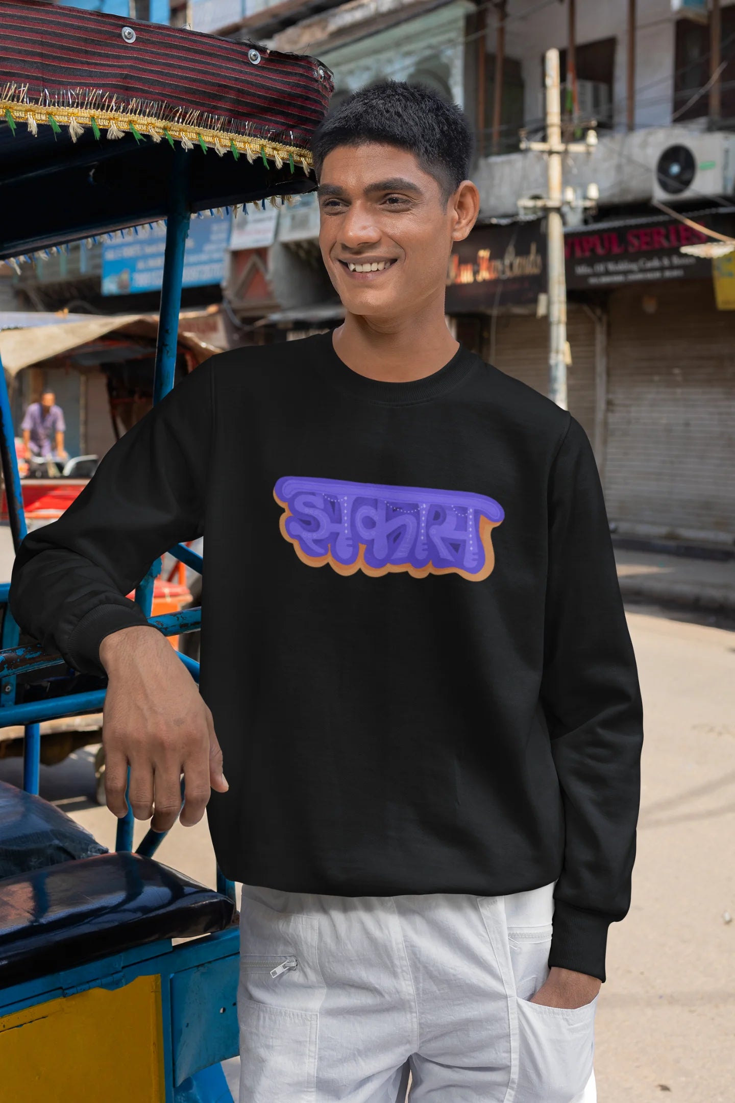 5th front view of a male model wearing an black sweatshirt featuring "Jhakas" in a stylish font.