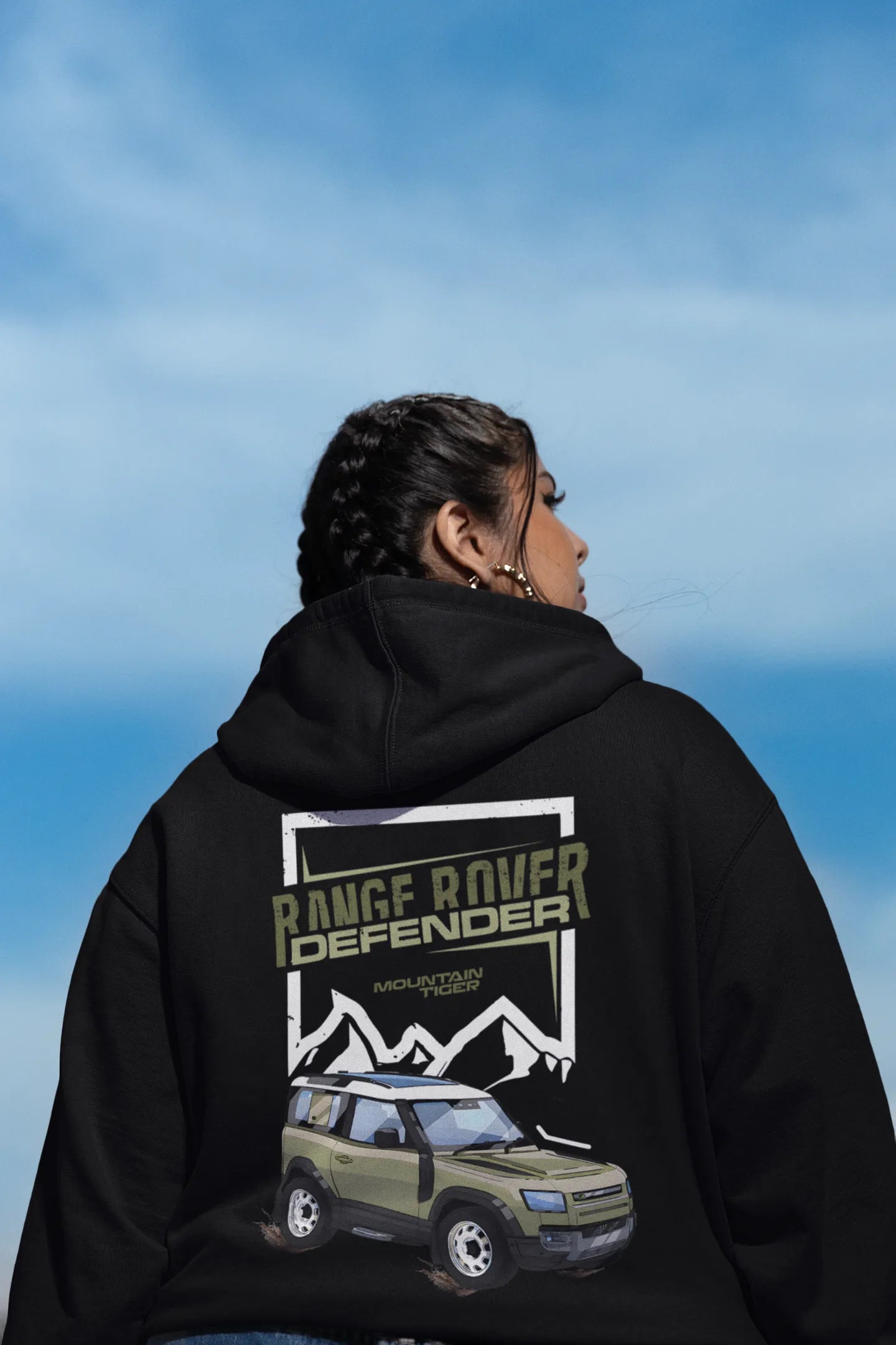 Back view of a female model wearing a black hoodie featuring a Range Rover Defender design, exuding power and ruggedness.