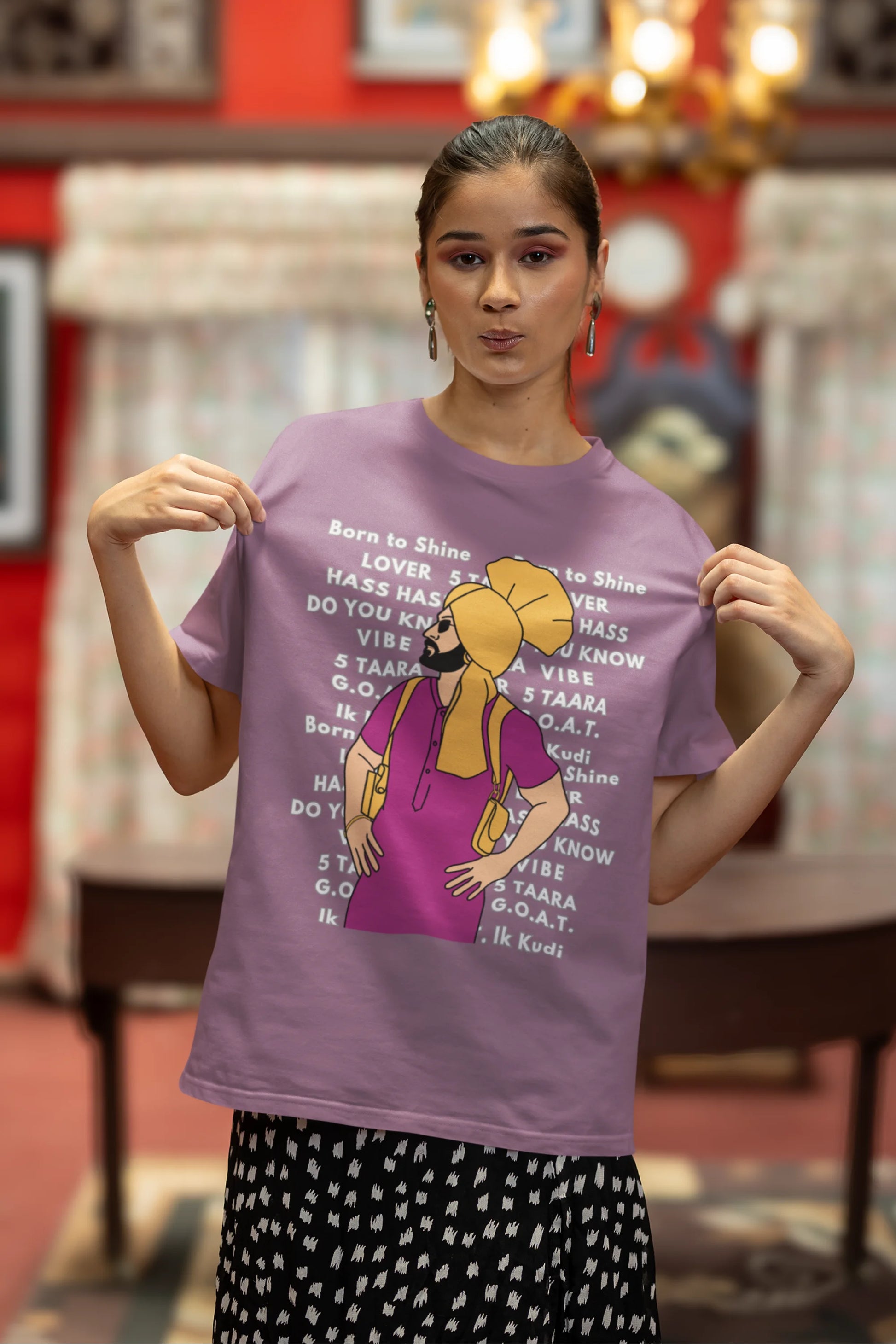 First image of a female model wearing a dirty purple oversized t-shirt with a Diljit Dosanjh portrait on a t-shirt with his album titles written in the background.