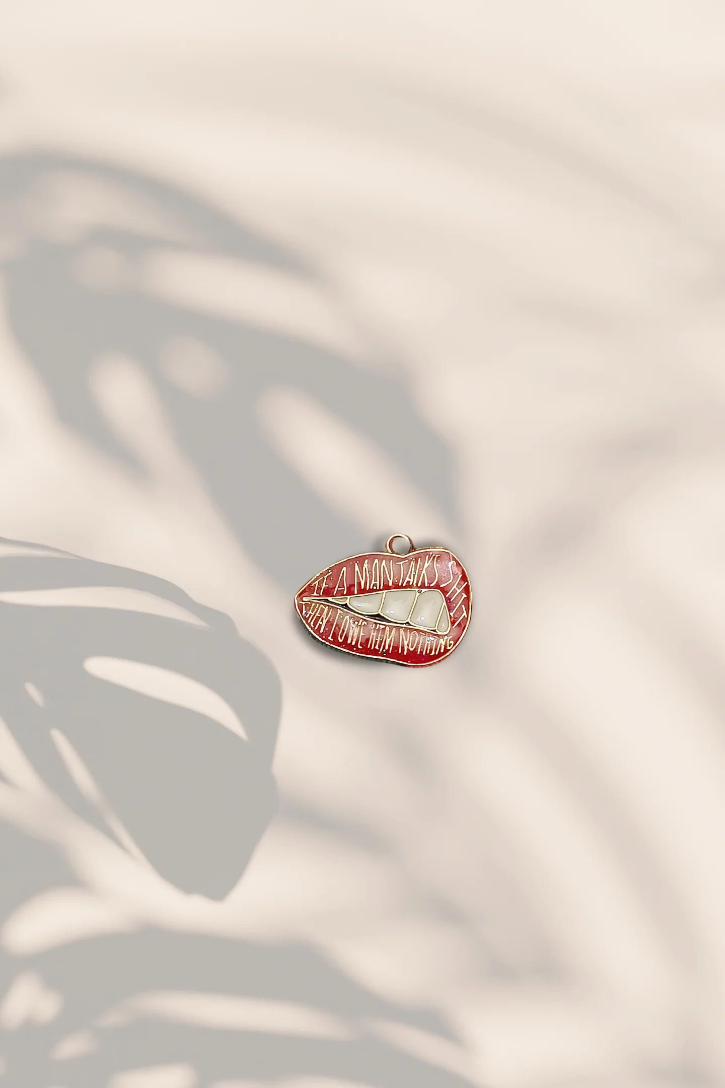 Second image of an charm featuring the Taylor Swift phrase "You Owe Him Nothing" on a lip design. Perfect for all Swifties.