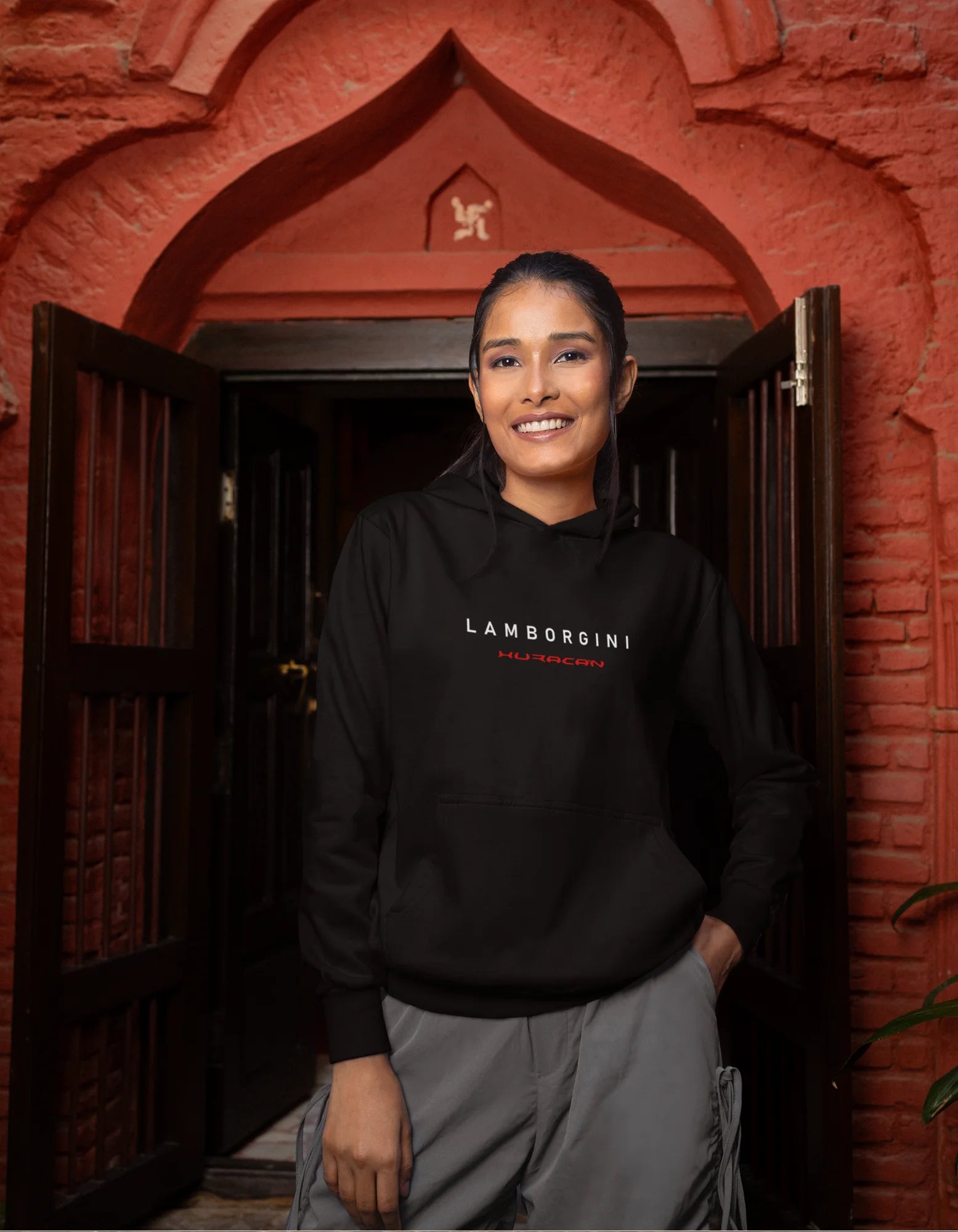 Third front view of a female model wearing a black hoodie featuring a Lamborghini Huracan design, exuding speed and power.