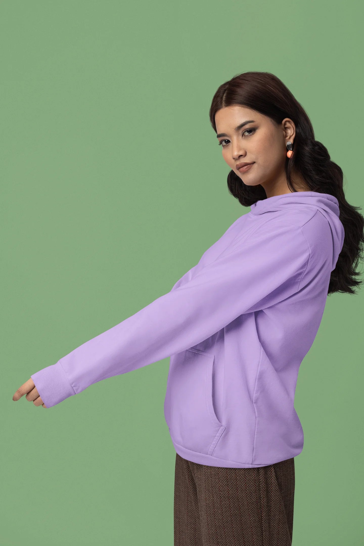 Third front view of female model wearing a lavender hoodie with a design of a cat dressed as a samurai, standing against a backdrop of waves and a rising sun.