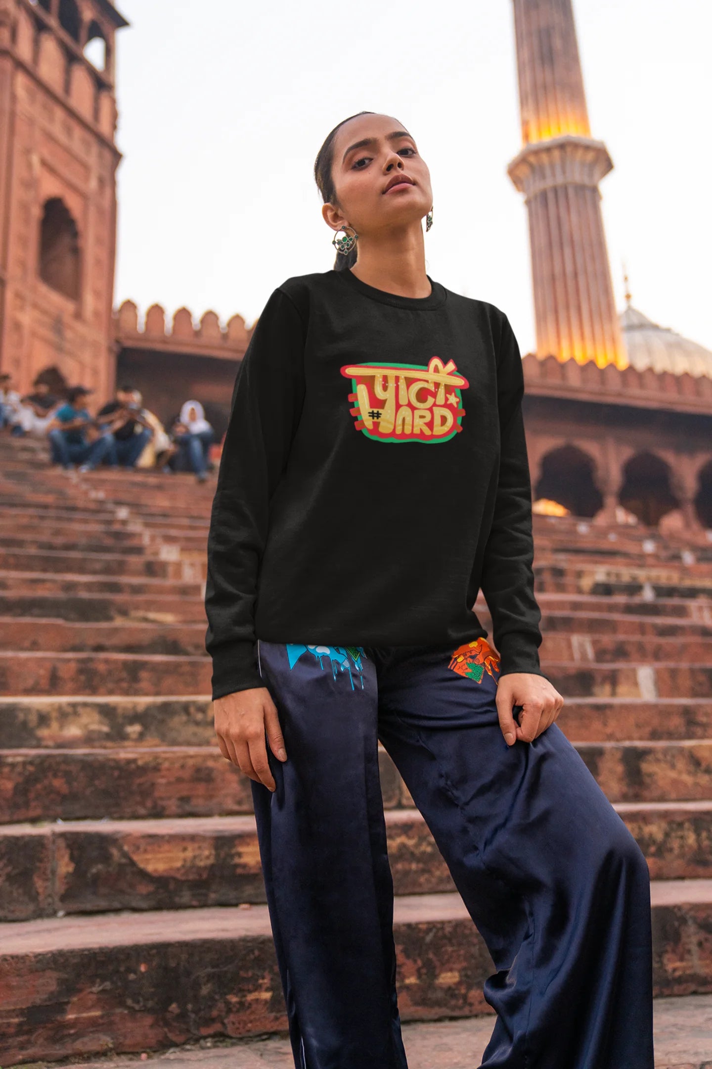 4th front view of a female model wearing a black oversized t-shirt with the phrase "Party Hard" in an energetic Hindi.