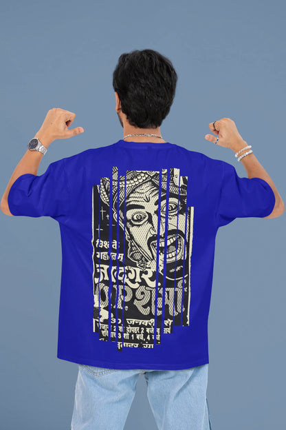 Back view of a male model wearing a royal blue oversized t-shirt with a design referencing "Bachpan" (childhood) and featuring a recognizable element or silhouette associated with the Indian magician "O P Sharma."