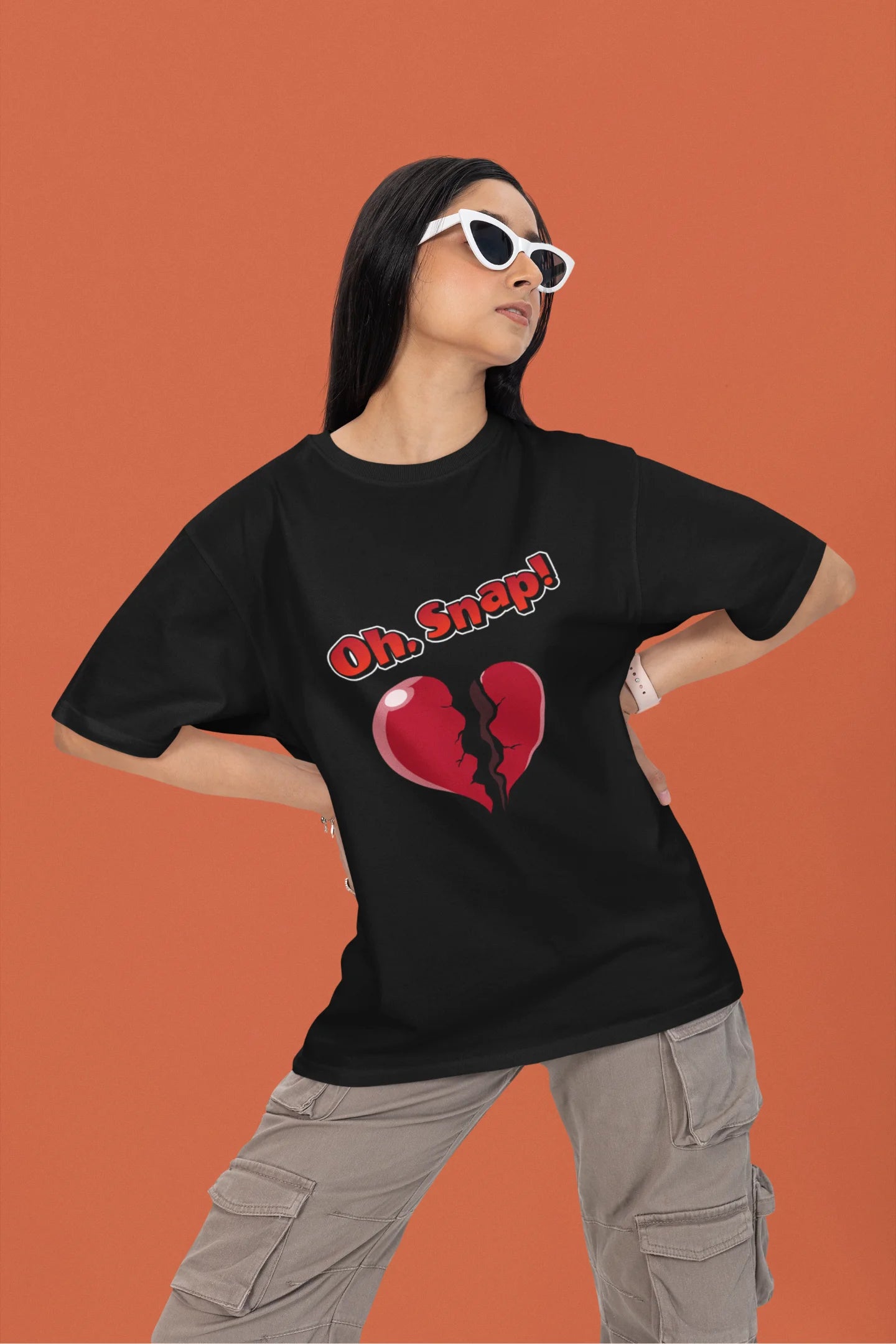 First front view of a female model wearing a black oversized t-shirt with the text "Oh Snap!" and a broken heart symbol underneath.