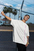 Side view of a male model wearing an off-white oversized t-shirt featuring a thought-provoking design of a man's bust with the text 