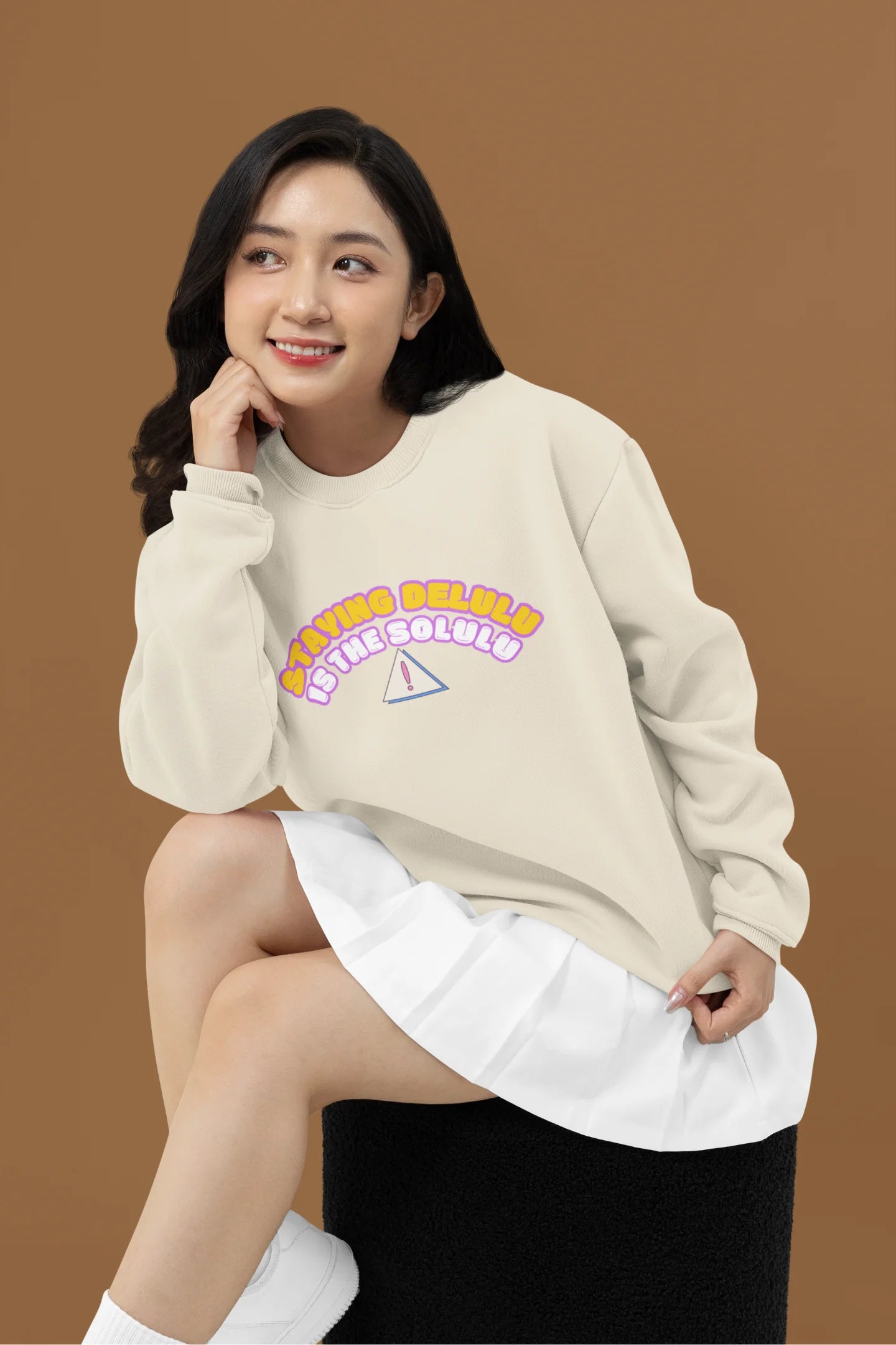 3rd front view of female model wearing a cream sweatshirt with the hilarious message "Stay Delulu" in a bold design. Ideal for those who love trendy slang and lighthearted humor.