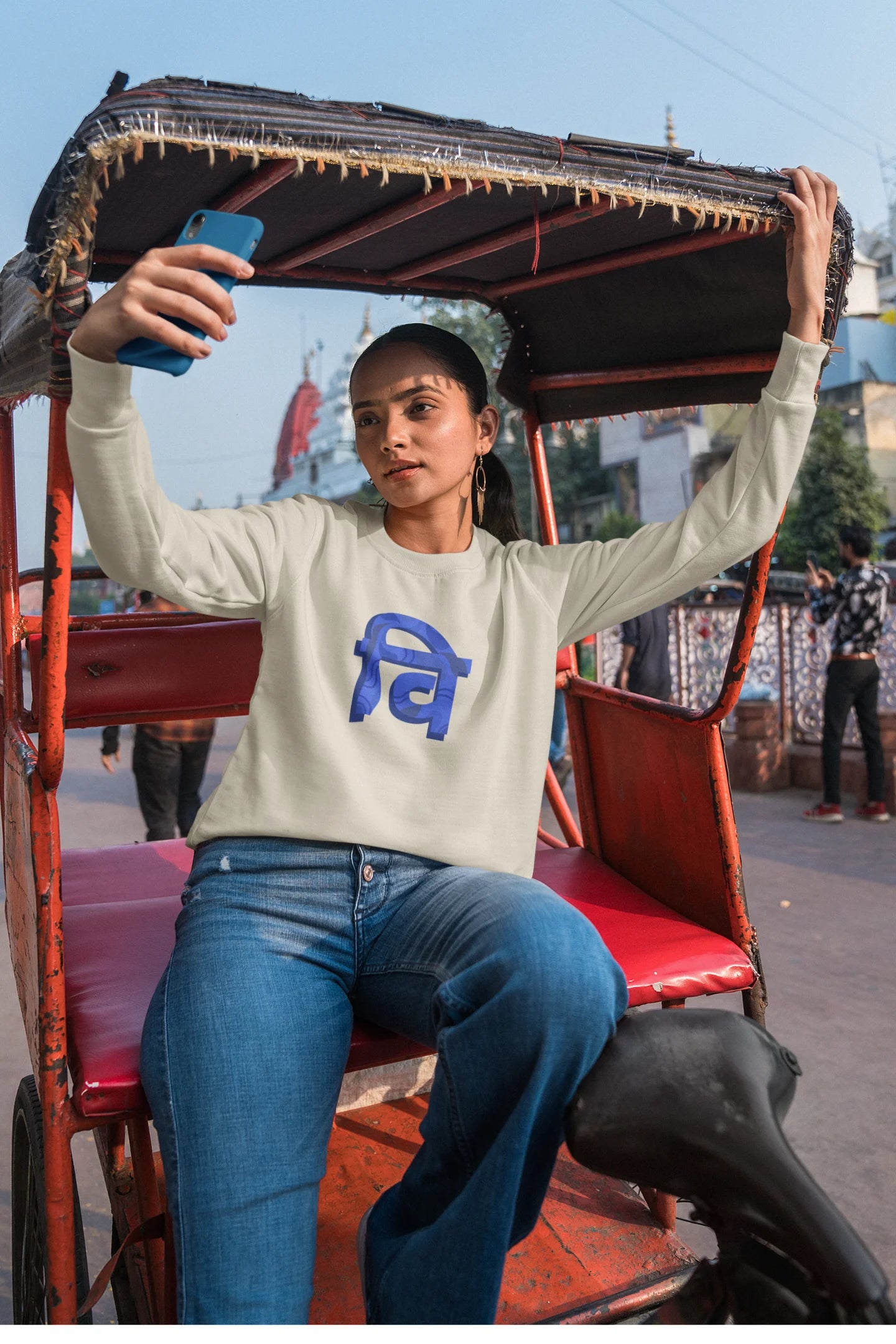 3rd front view of a female model wearing a cream sweatshirt with the phrase "Vichitra Pranee" (meaning "Strange being" or "alien") in a stylish Hindi font.