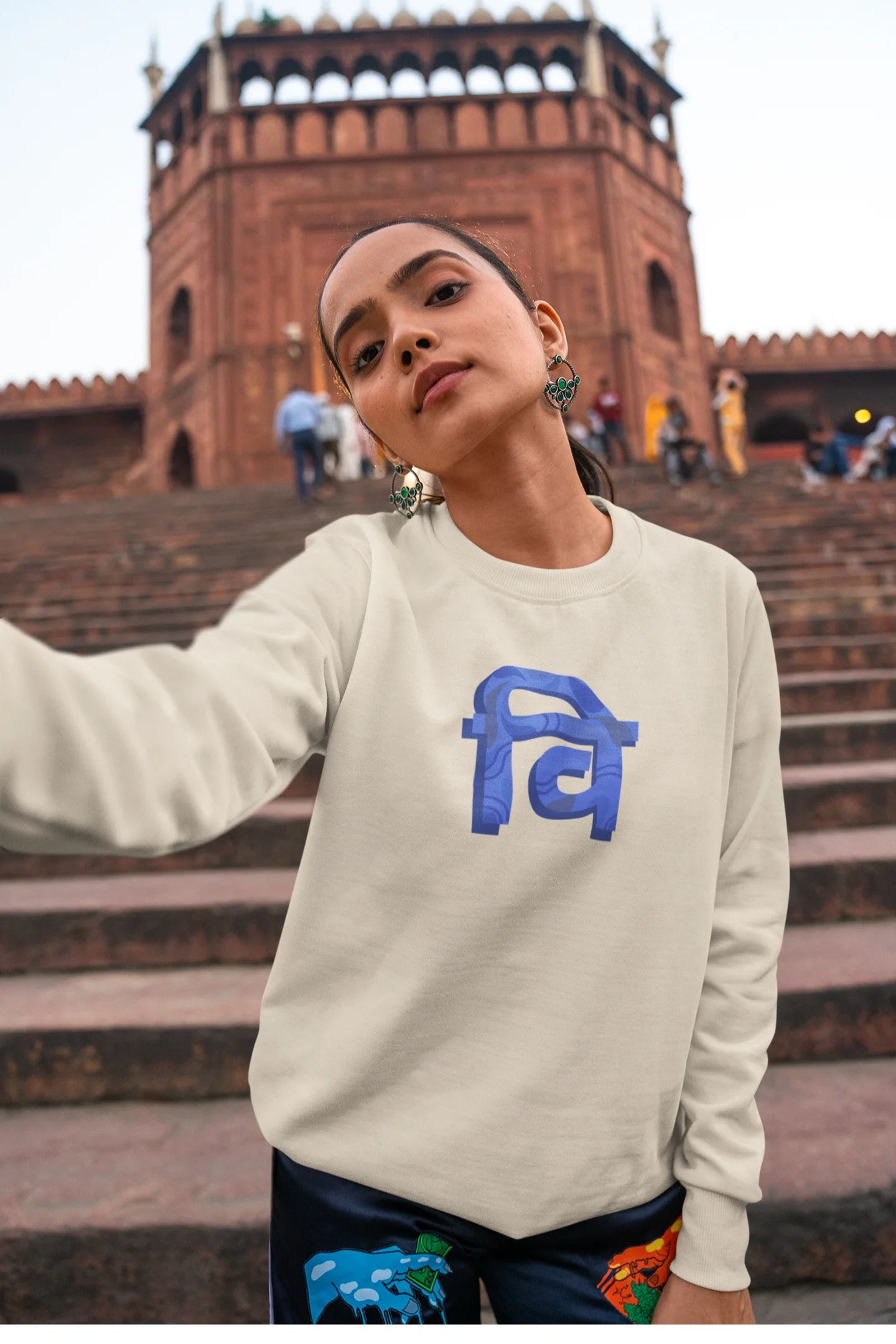 4th front view of a female model wearing a cream sweatshirt with the phrase "Vichitra Pranee" (meaning "Strange being" or "alien") in a stylish Hindi font.
