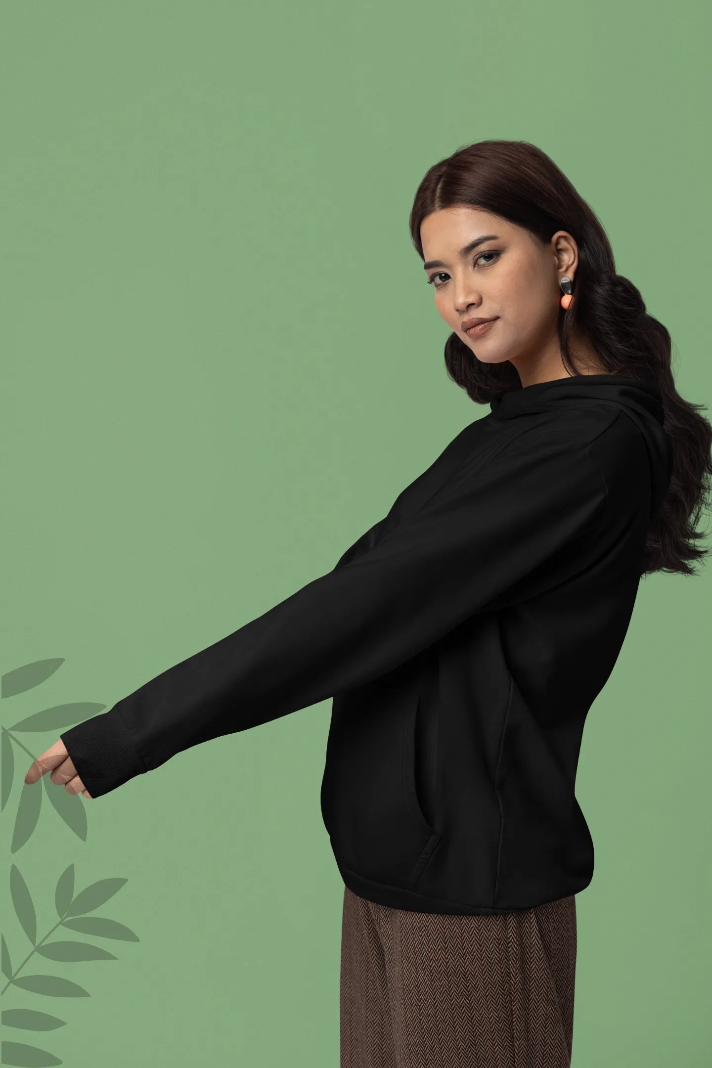 Third front view of a female model wearing a black hoodie with a design of a wildcat sitting on ocean waves.
