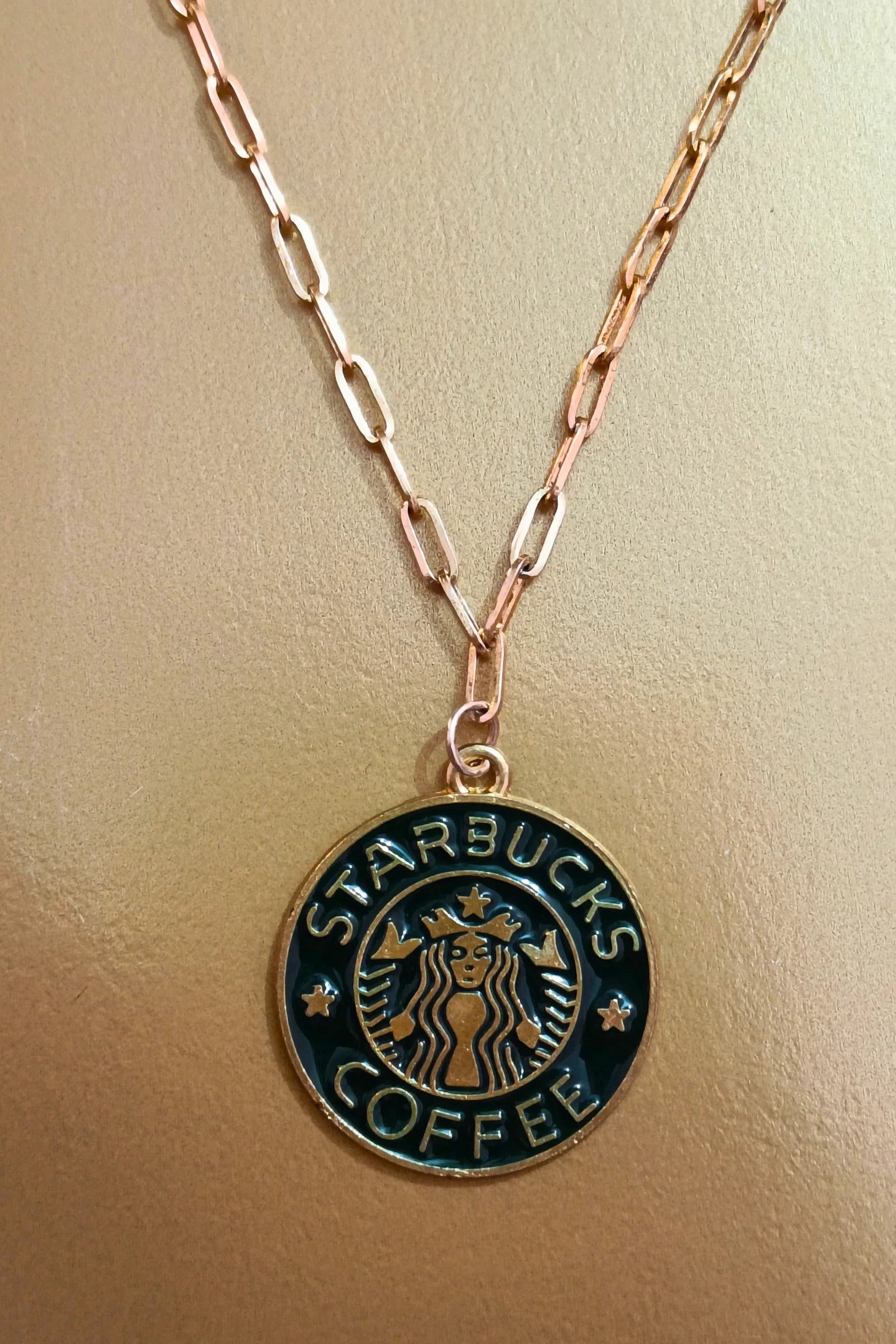 2nd view of a gold chain necklace with a small pendant featuring the Starbucks logo.