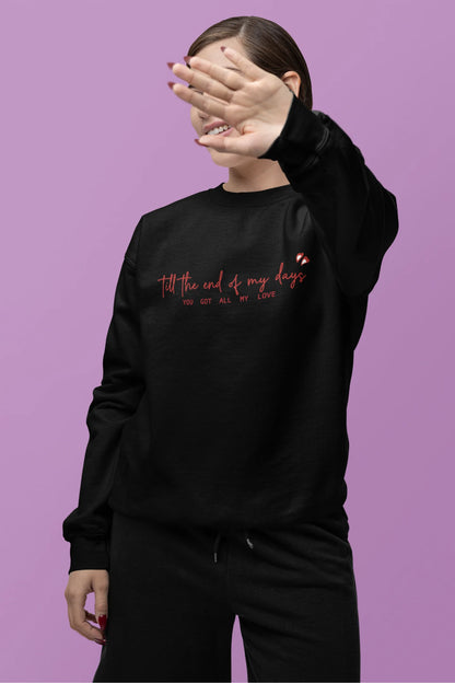 Second front view of a female model wearing a black sweatshirt with a heart design and the text "All My Love".