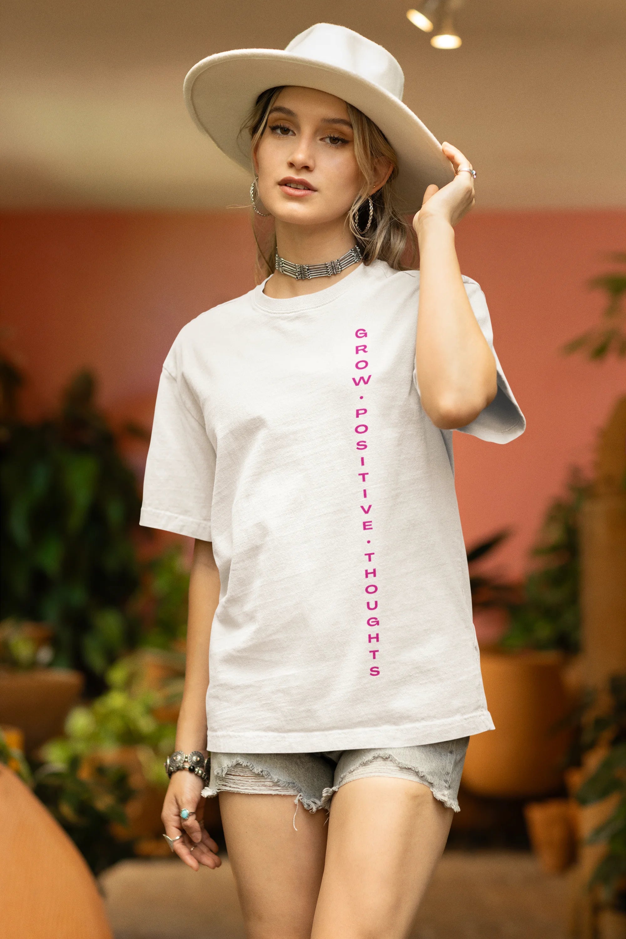 Side view of a female model wearing an off-white oversized t-shirt featuring a thought-provoking design of a man's bust with the text "Think It's Free of Cost." Ideal for those who love funny clothing and the importance of mindful communication.