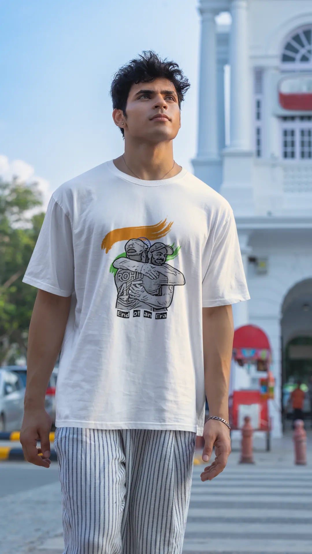 Second front view of a male model wearing an off-white oversized t-shirt featuring a photo of Virat Kohli and Rohit Sharma in a celebratory hug after the World Cup 2024 final. Ideal for Indian cricket fans who want to honor the team's victory and potentially a changing of the guard.